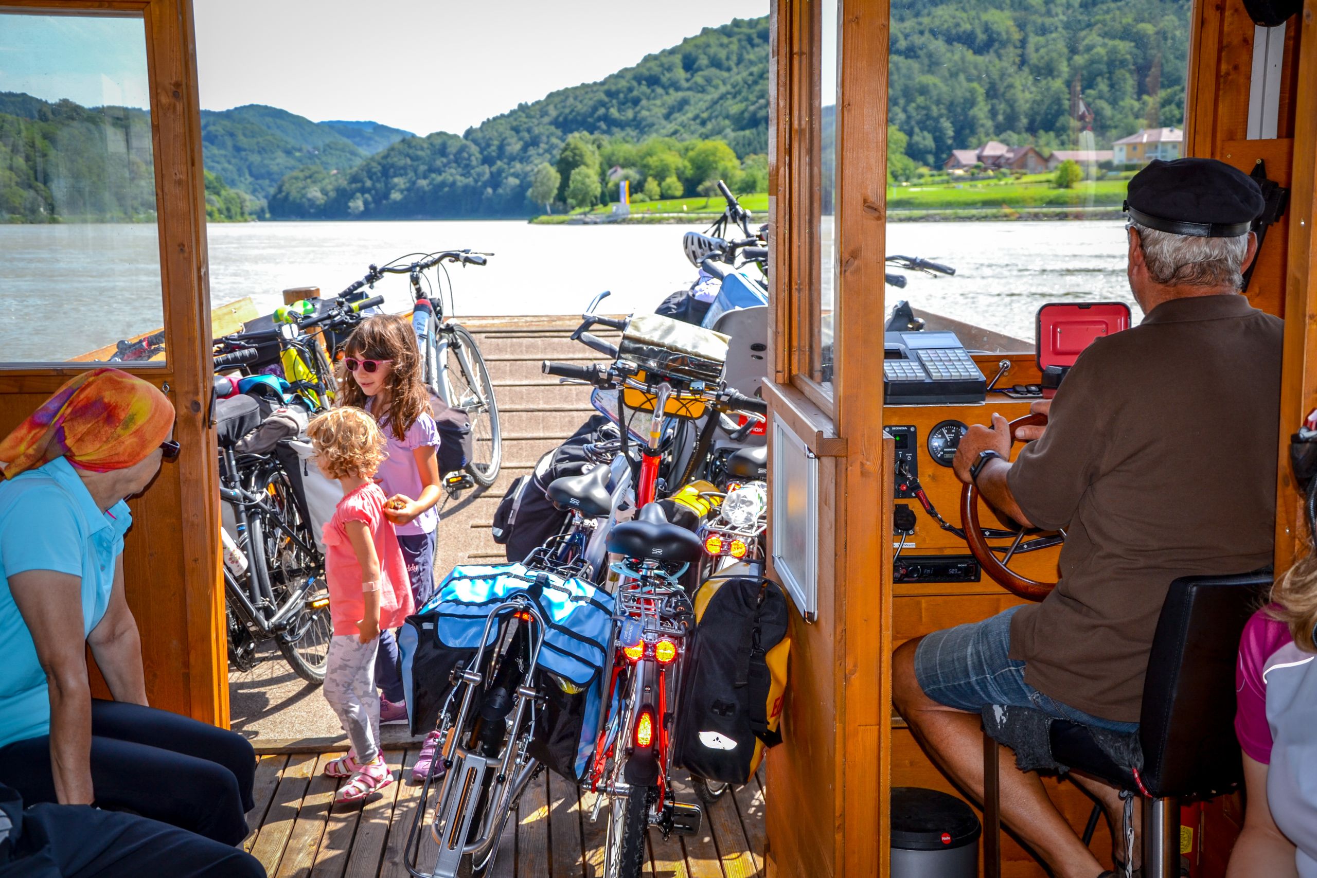 Famiglia con bambini intenti ad attraversare la sponda del Danubio in traghetto, tra Linz e Vienna, Austria