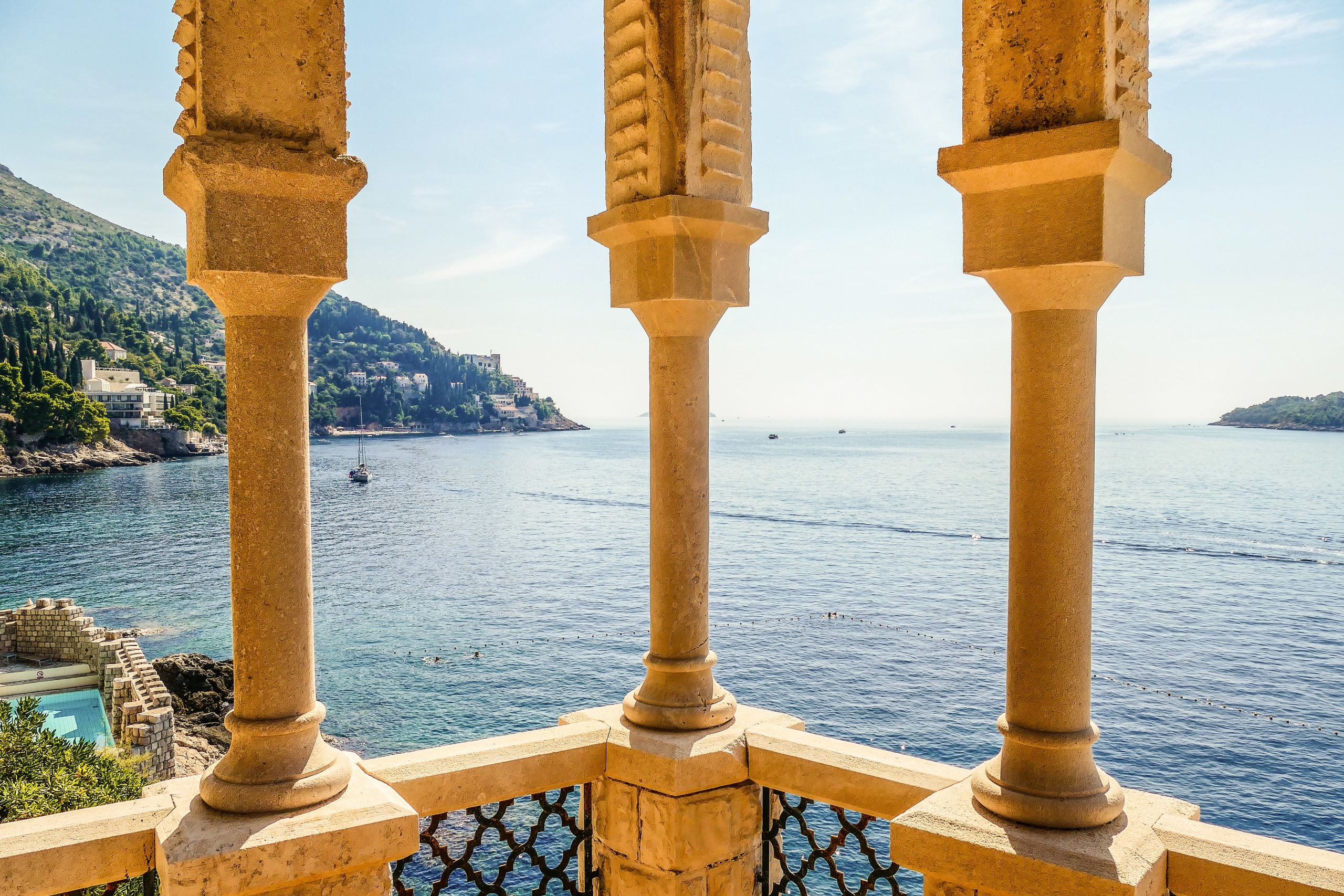 Dettaglio di colonne in pietra con vista sul mare.