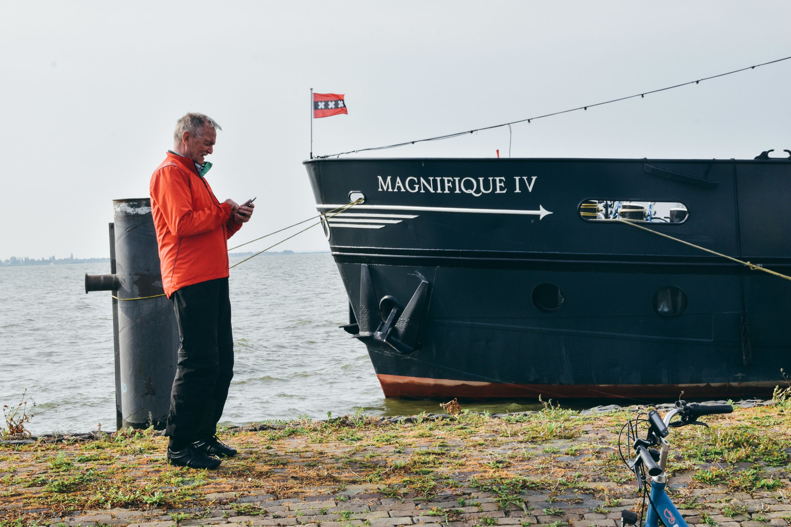 Turista che osserva la barca "Magnifique IV" al molo