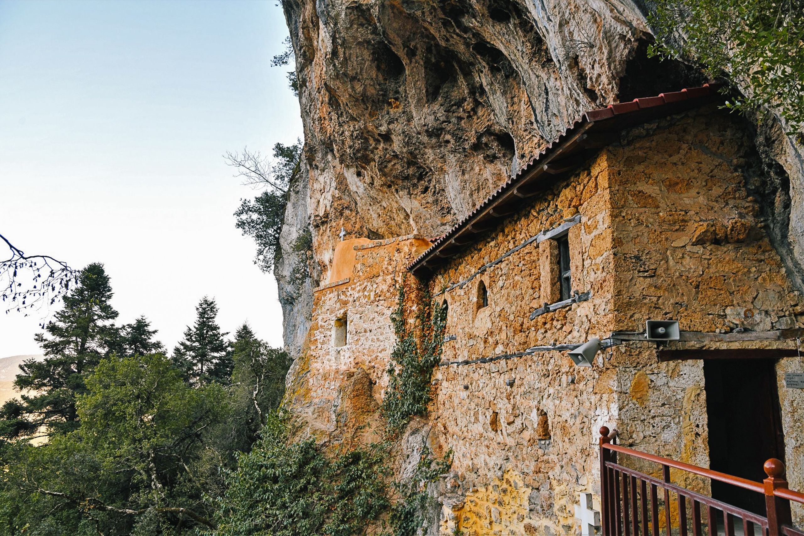 Edificio antico in pietra addossato a una parete rocciosa
