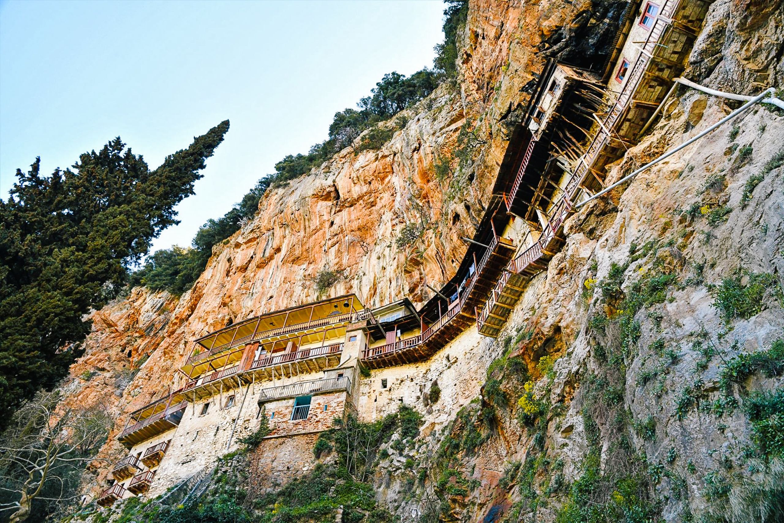 Monastero costruito lungo una parete rocciosa, integrato nella natura circostante.