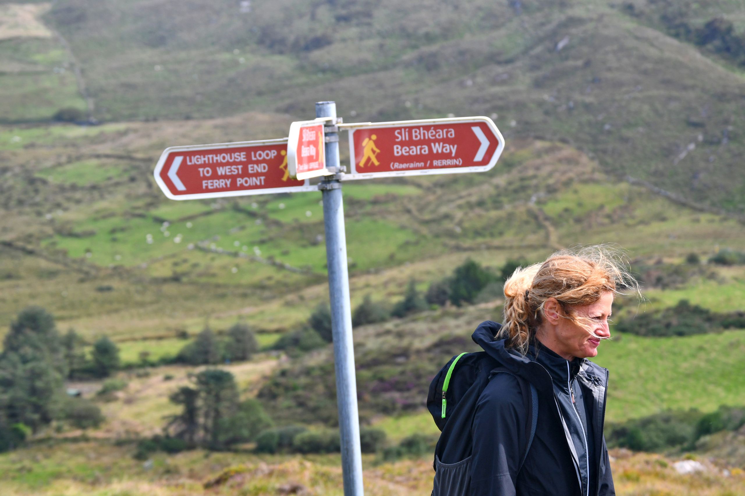 Escursionista vicino a un segnale turistico che indica la direzione lungo il percorso tra Cork e Kerry.