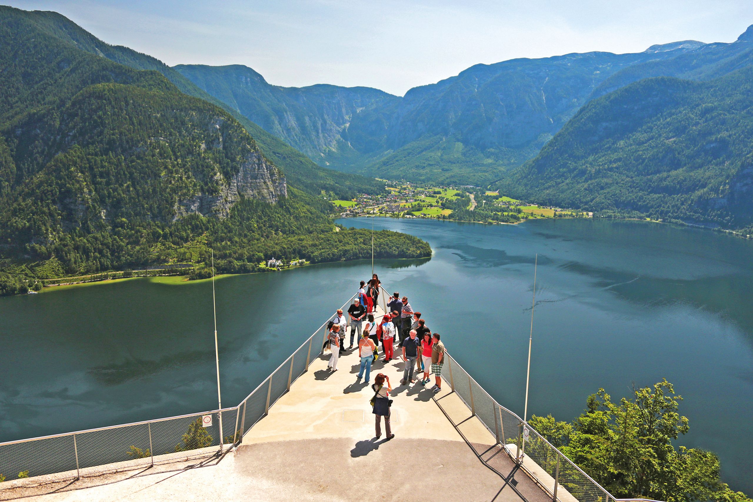 Turisti su una terrazza panoramica con vista sul lago Hallstättersee e le montagne circostanti.