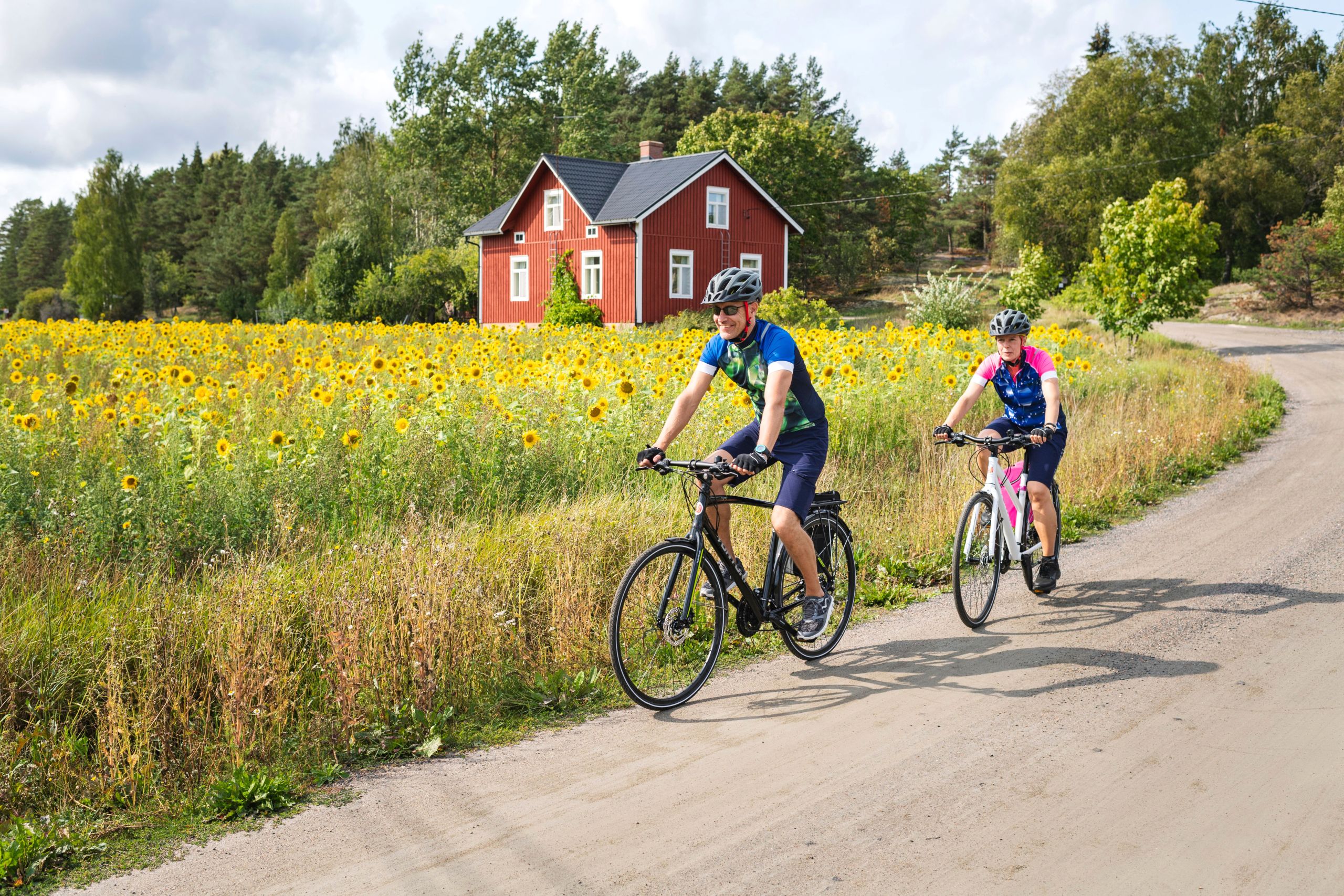 Coppia in bicicletta lungo un sentiero circondato da prati e boschi, nell'arcipelago di Turku.