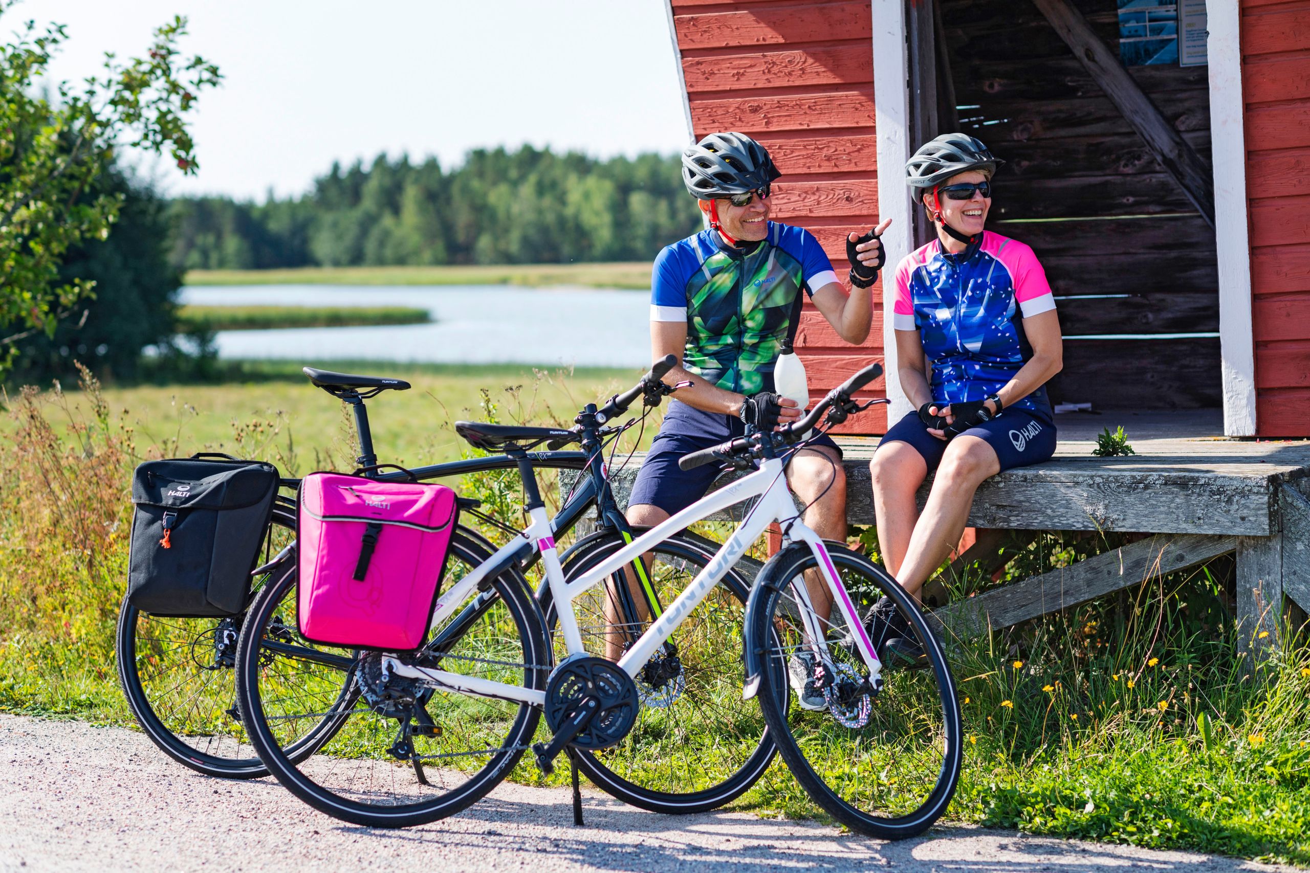 Coppia in bicicletta durante una sosta davanti una casa rossa tradizionale finlandese.