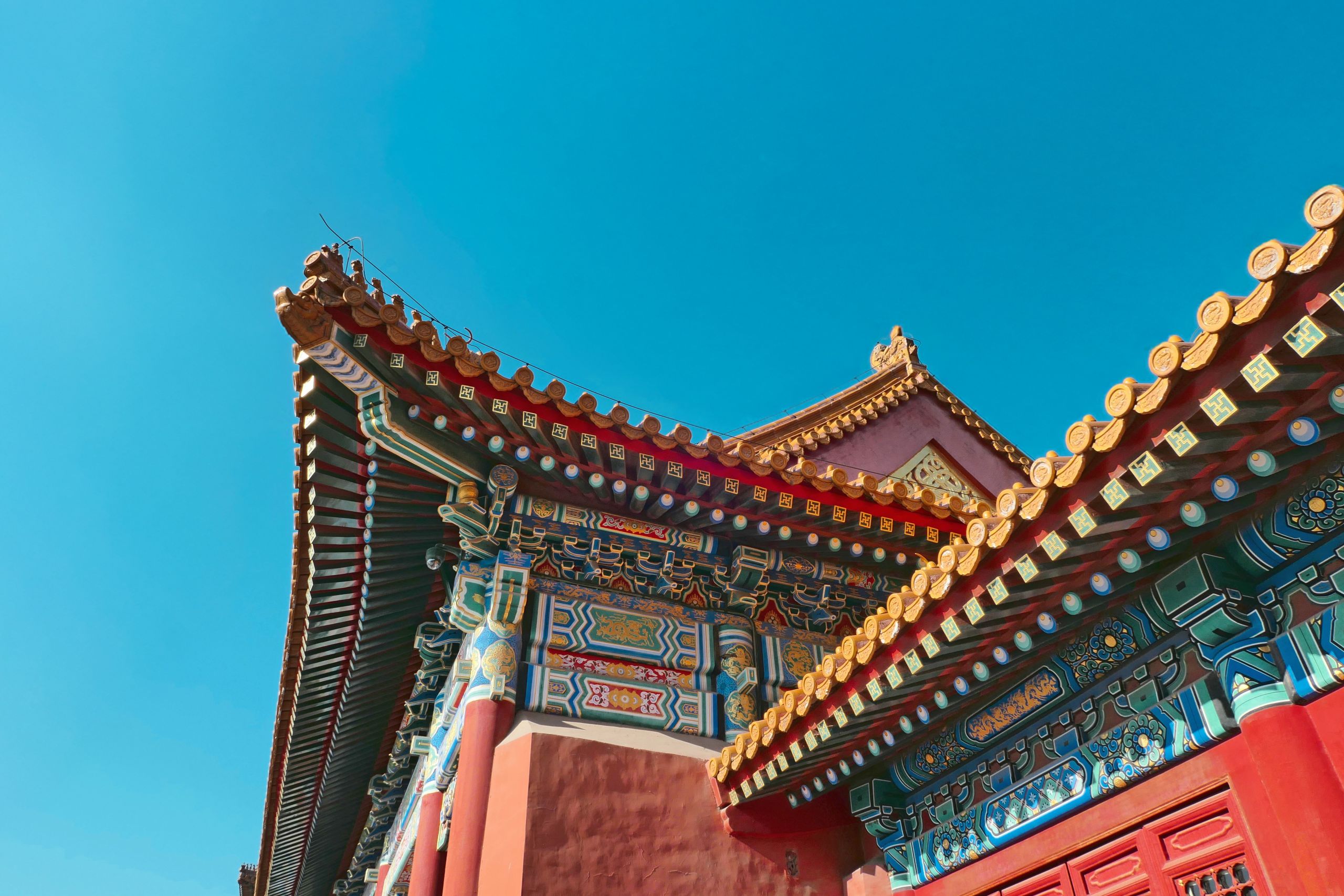Dettaglio del tetto decorato del Palazzo d’Estate a Pechino con cielo azzurro sullo sfondo.