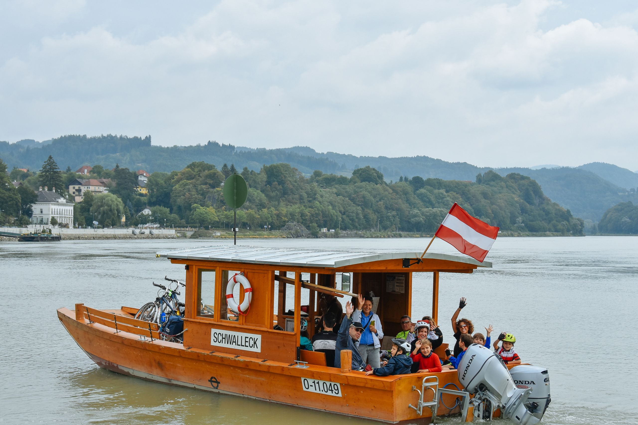 Gruppo di ciclisti intenti ad attraversare il Danubio su un traghetto, vacanza per famiglie, Austria