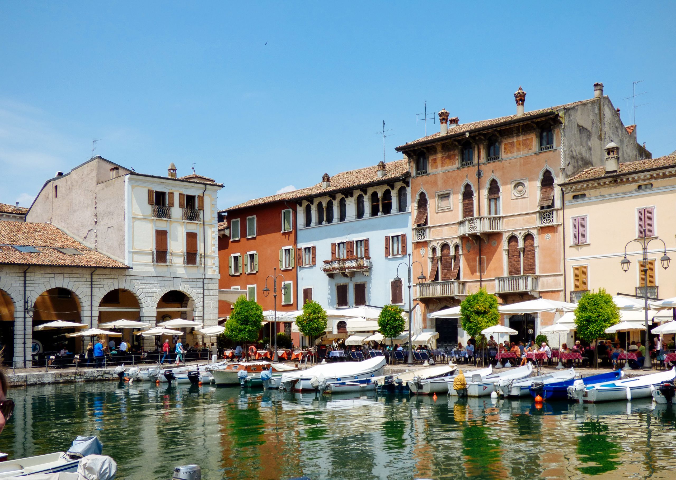 Case e ristoranti in riva al lago di Garda, tavolini all'aperto, imbarcazioni, vacanza ecosostenibile, Desenzano del Garda