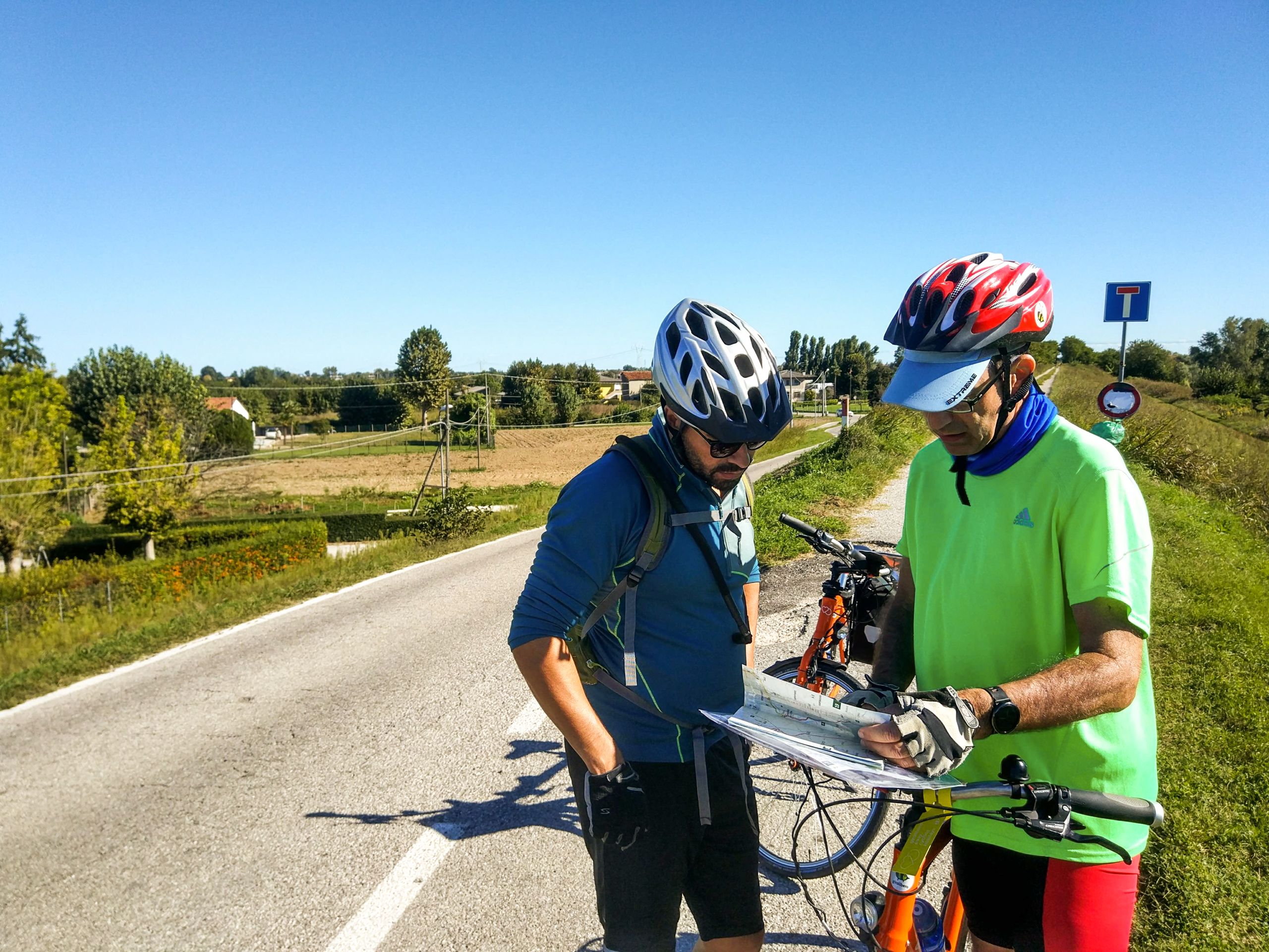 Zwei Radfahrer auf der Straße, die eine Karte mit Wanderwegen prüfen, um den besten Radweg zu finden