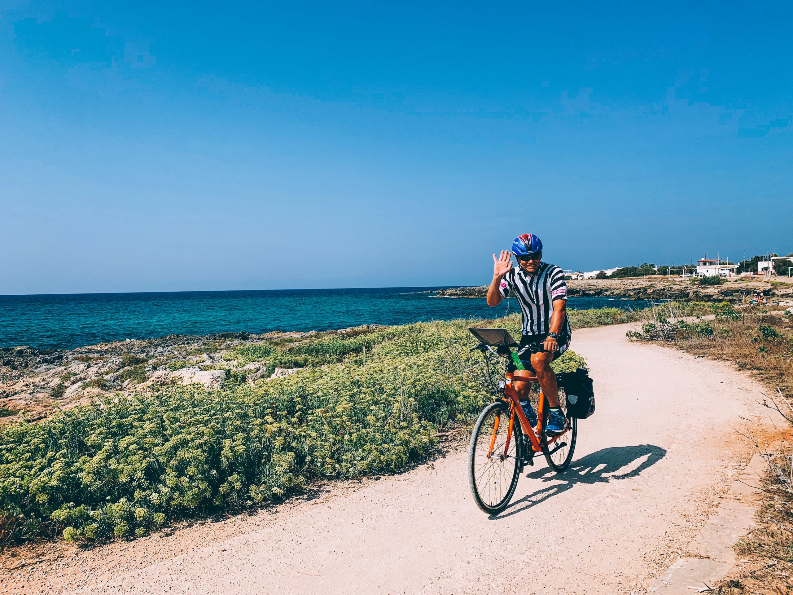 Mann fährt ein oranges Fahrrad im Sand in der Nähe des Meeres, Apulien