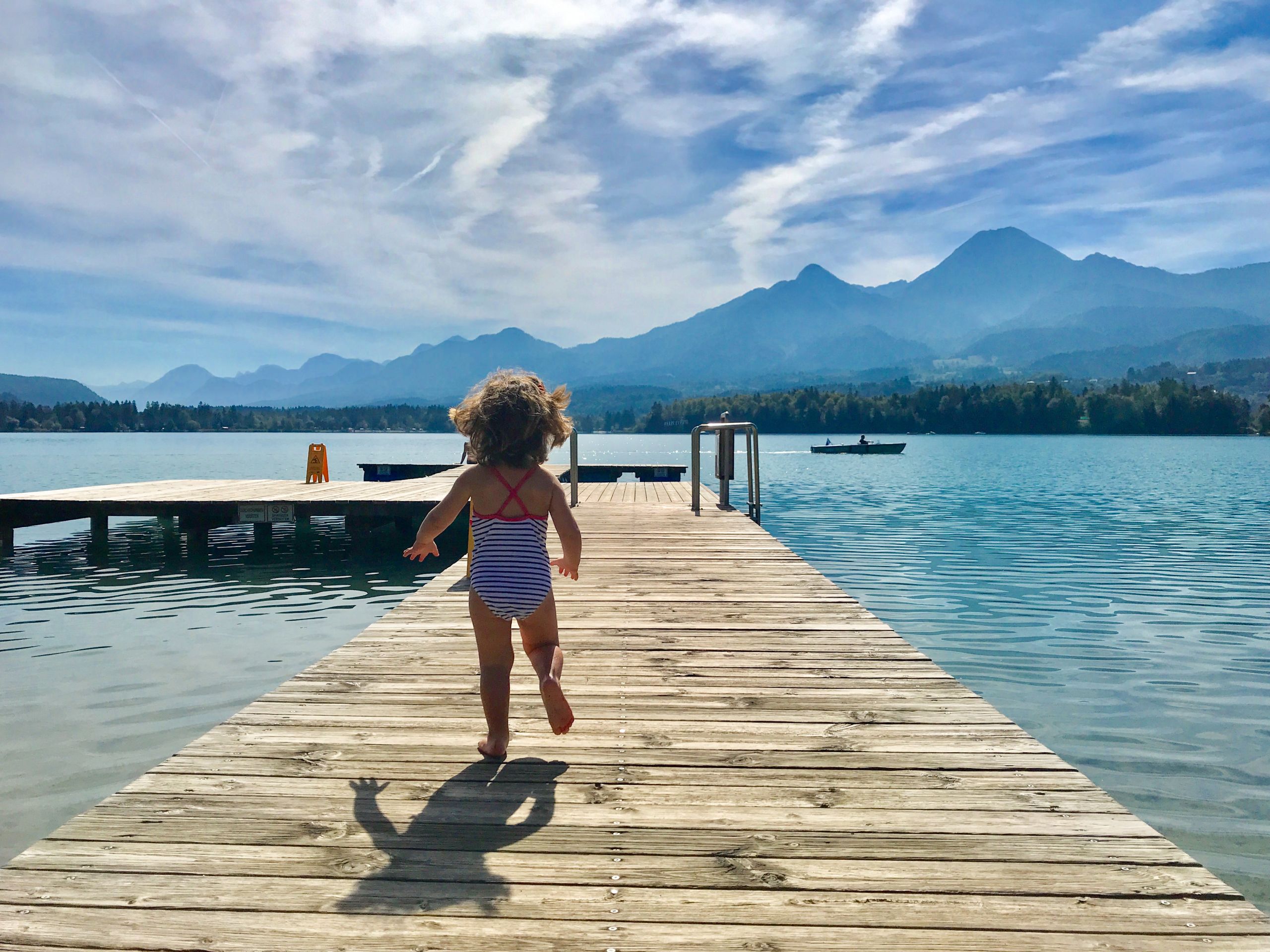 Bambina in costume che corre su una piattaforma in legno per fare un tuffo nel fiume Drava, vacanza in bici, Austria