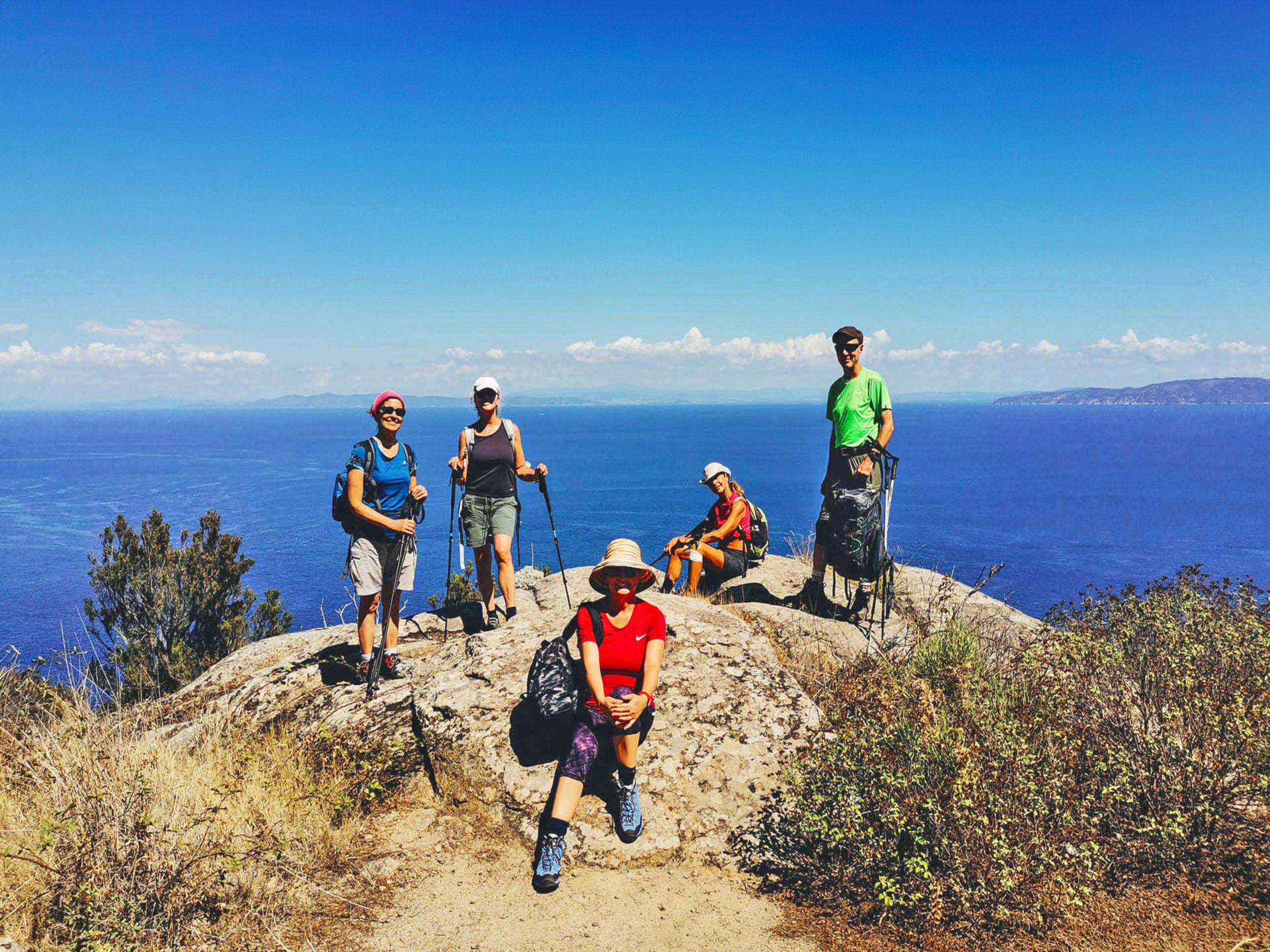 Escursionisti in posa per una foto di gruppo lungo un sentiero costiero panoramico nell'isola del Giglio, Toscana