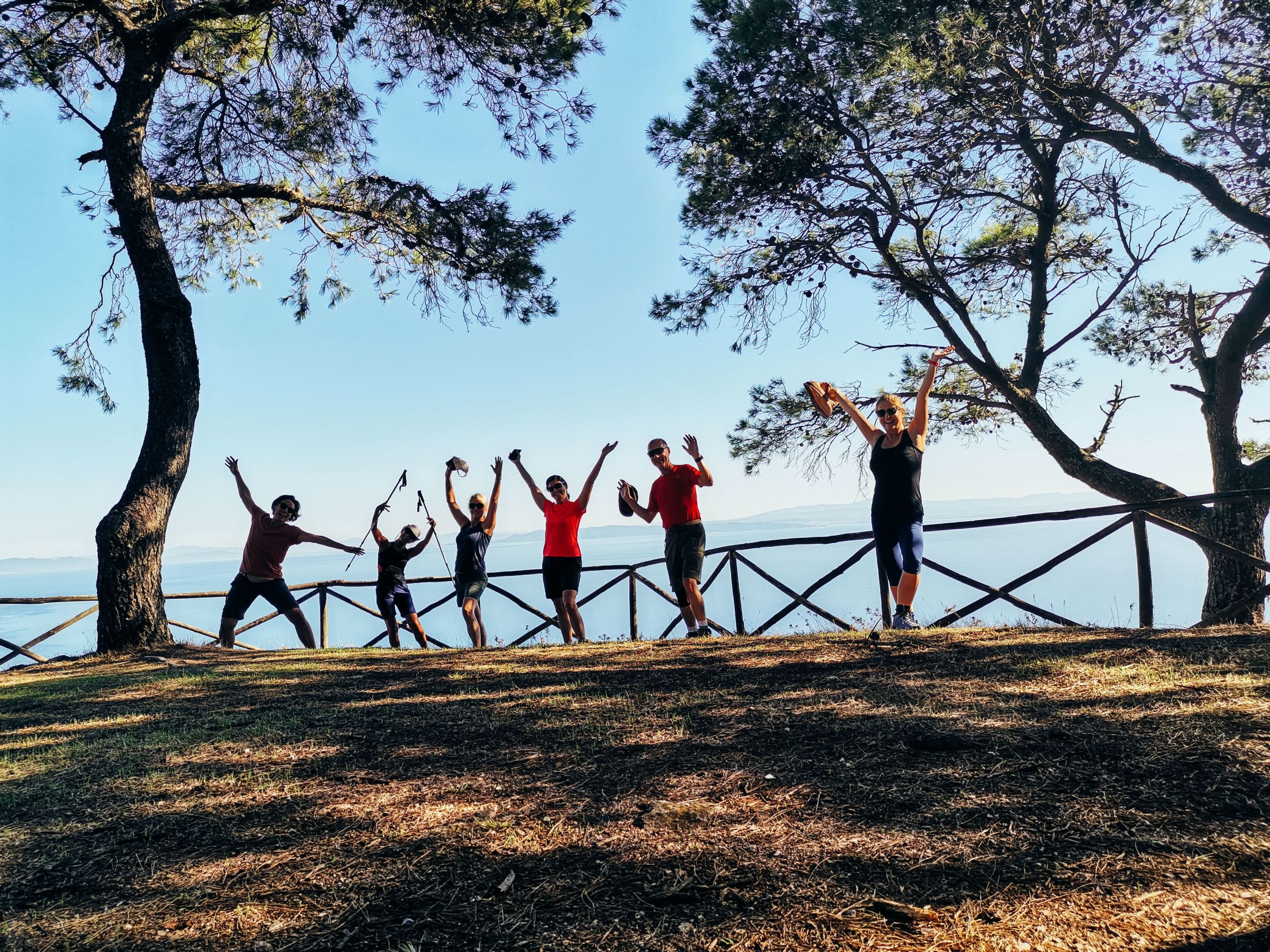 Gruppo di camminatori in posa tra due alberi, trekking nell'isola del Giglio, relax, slow tourism, Toscana