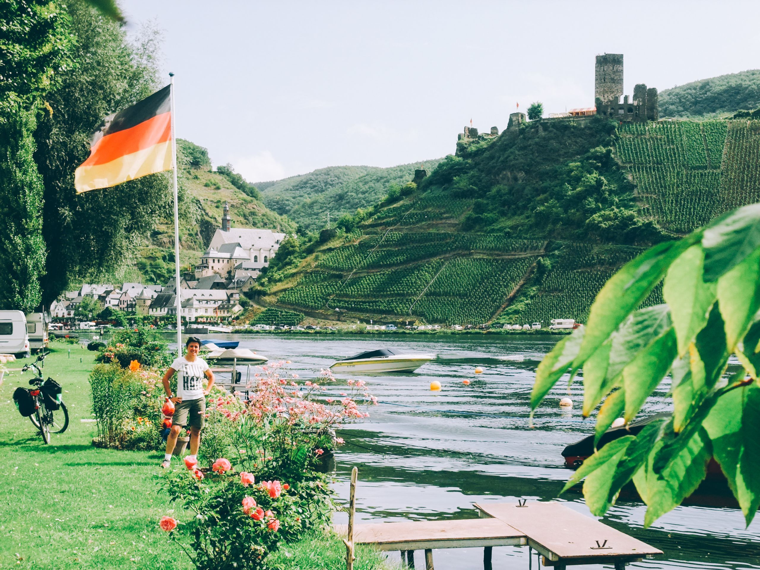 Fahrrad geparkt entlang der Mosel in der Nähe einer deutschen Flagge und Weinbergen, Deutschland.