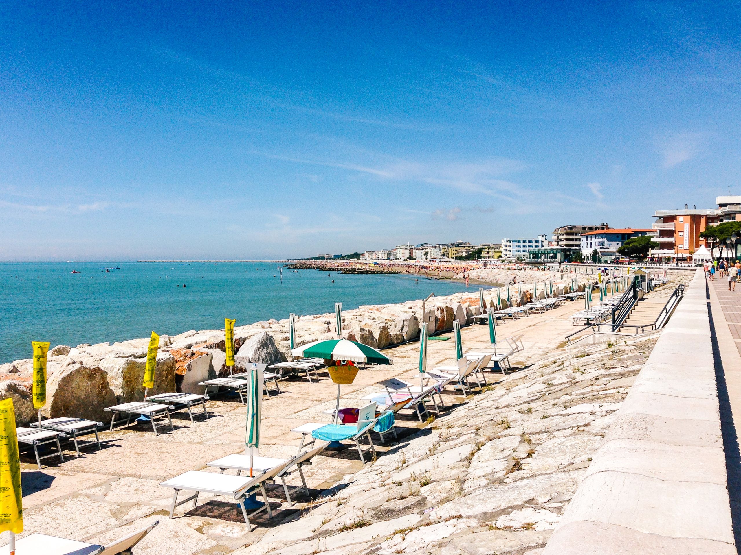 Seaside promenade in Poreč with umbrellas and sun loungers along the beach, Croatia.