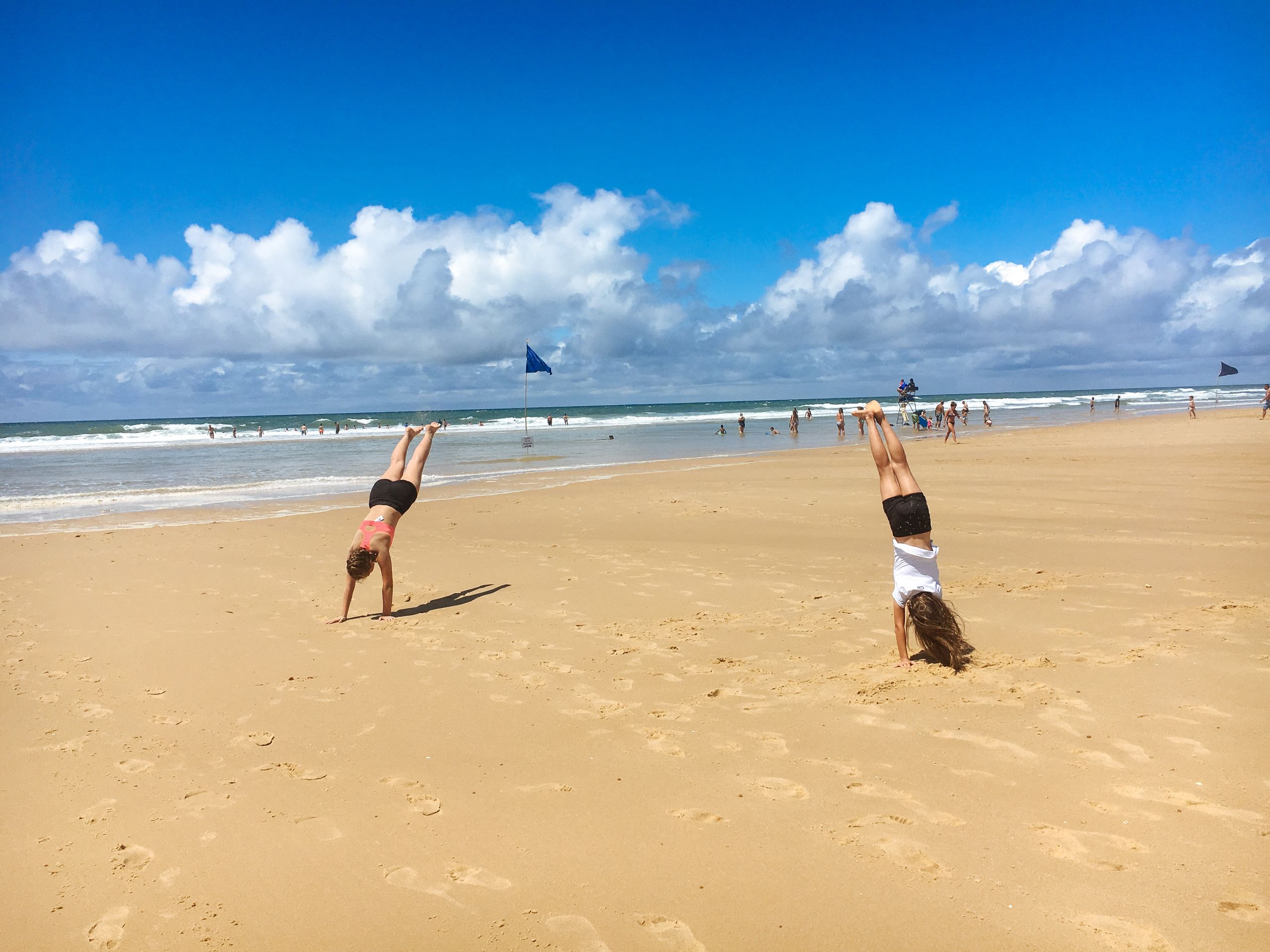 Persone che giocano sulla spiaggia sabbiosa della Baia di Arcachon sotto un cielo sereno.