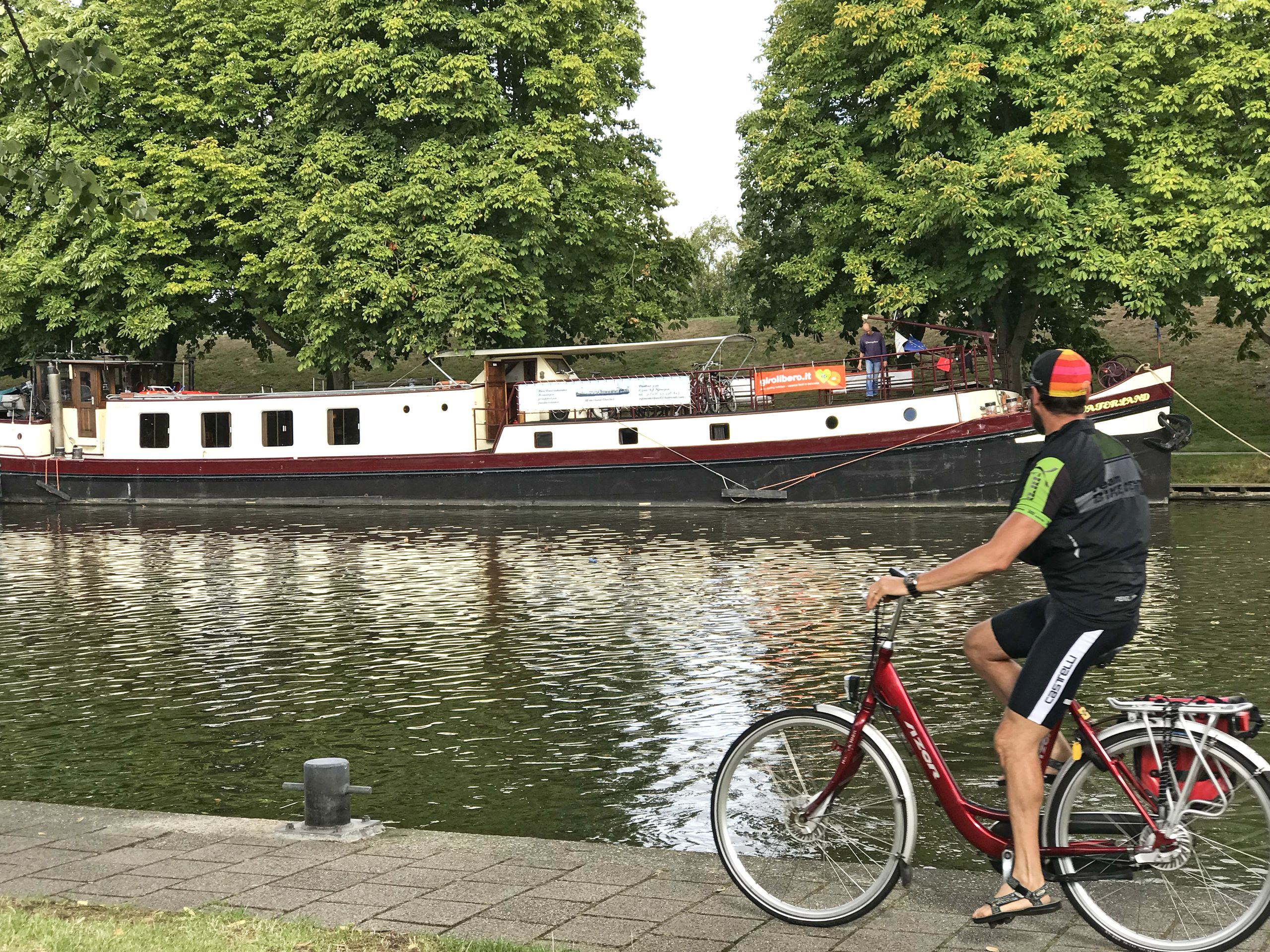 Radfahrer mit Fahrrad auf einem Radweg entlang eines Kanals in den Niederlanden, Girolibero-Radreisen