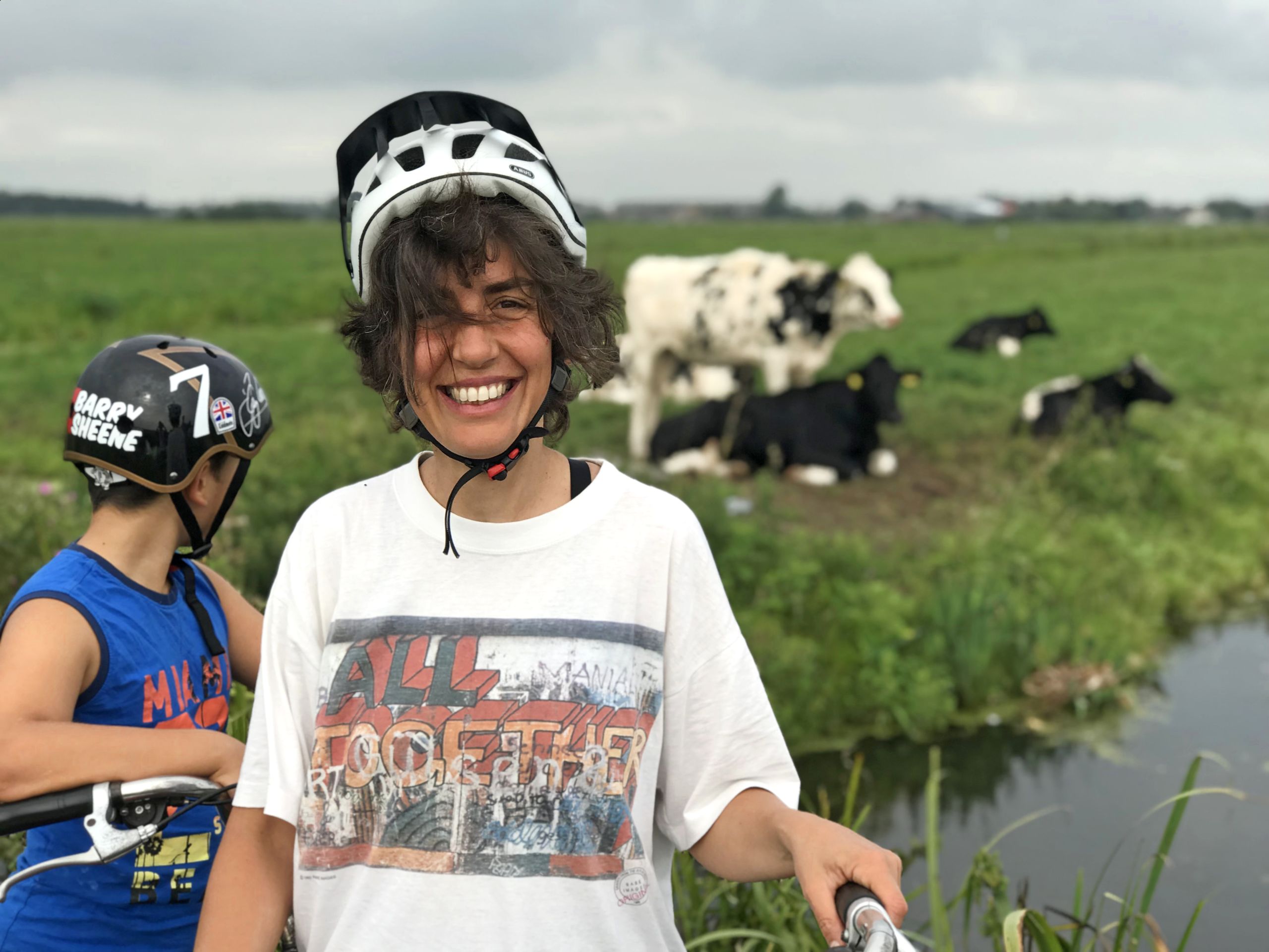 Smiling family with a cycling helmet and a green hilly background