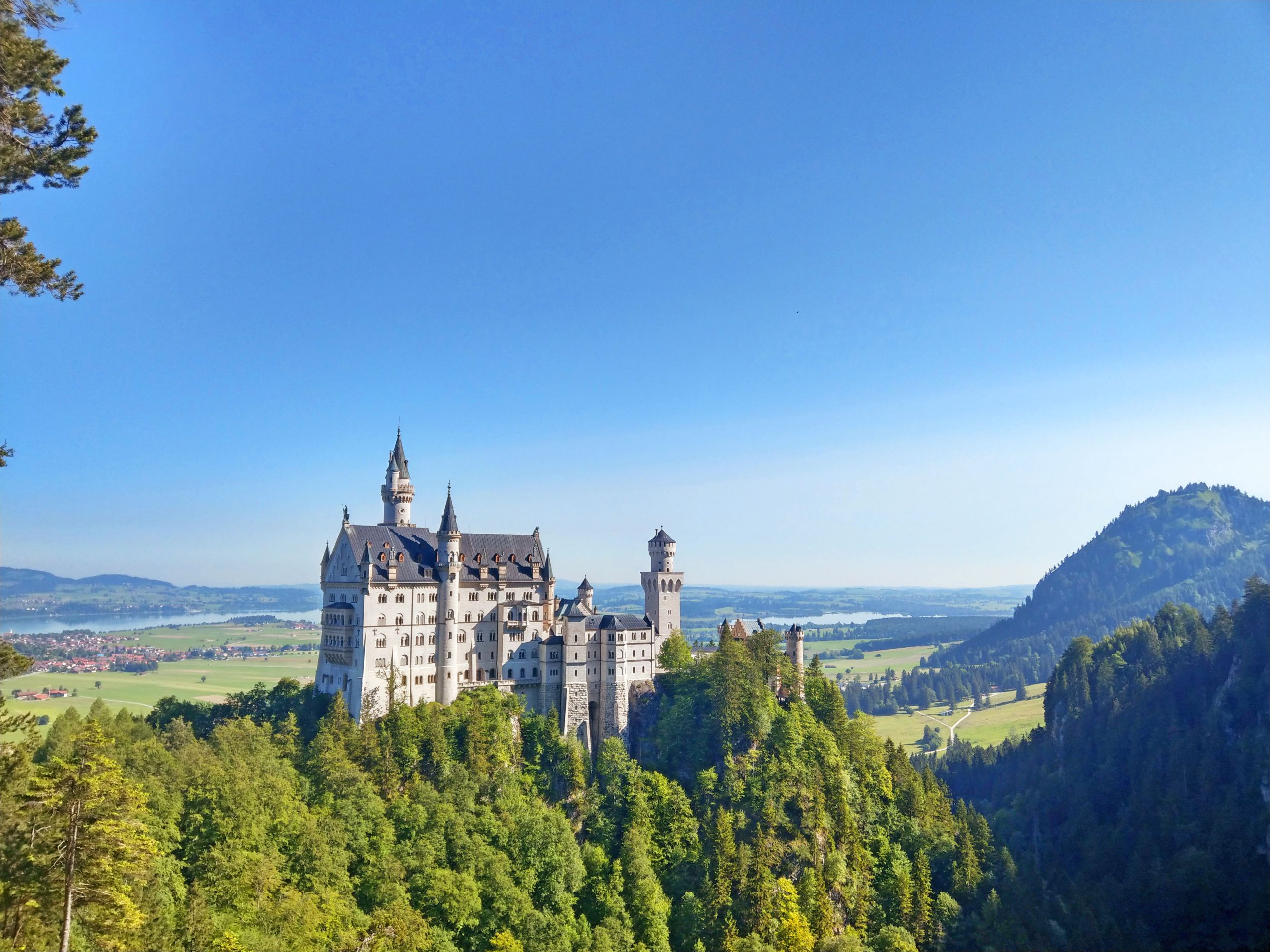 Castello Neuschwanstein visto da lontano tra le colline boscose, Via Claudia Augusta, Germania