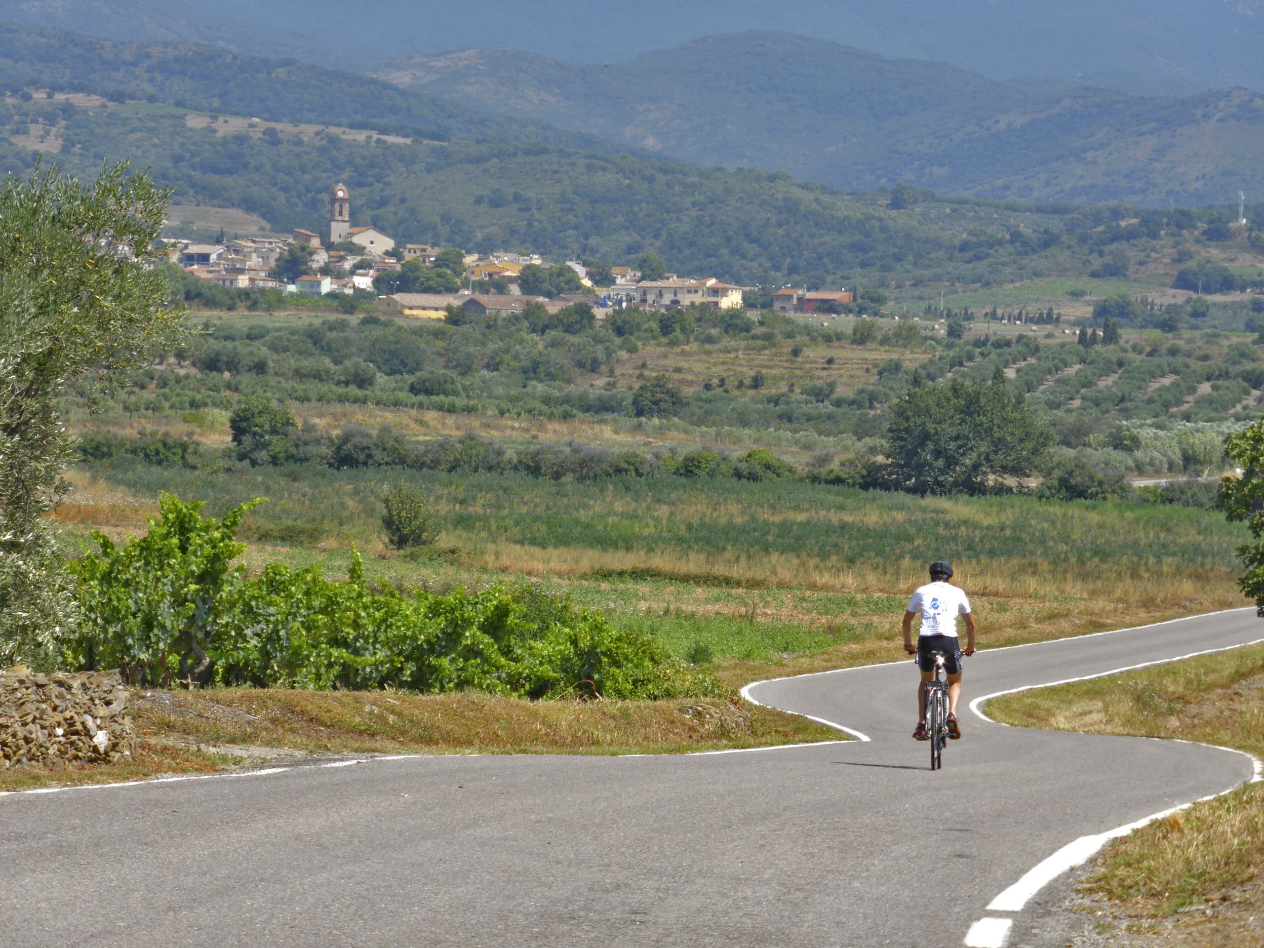 Ciclista che percorre una strada panoramica tra le colline della Catalogna, Spagna, viaggi in bici "Girolibero"