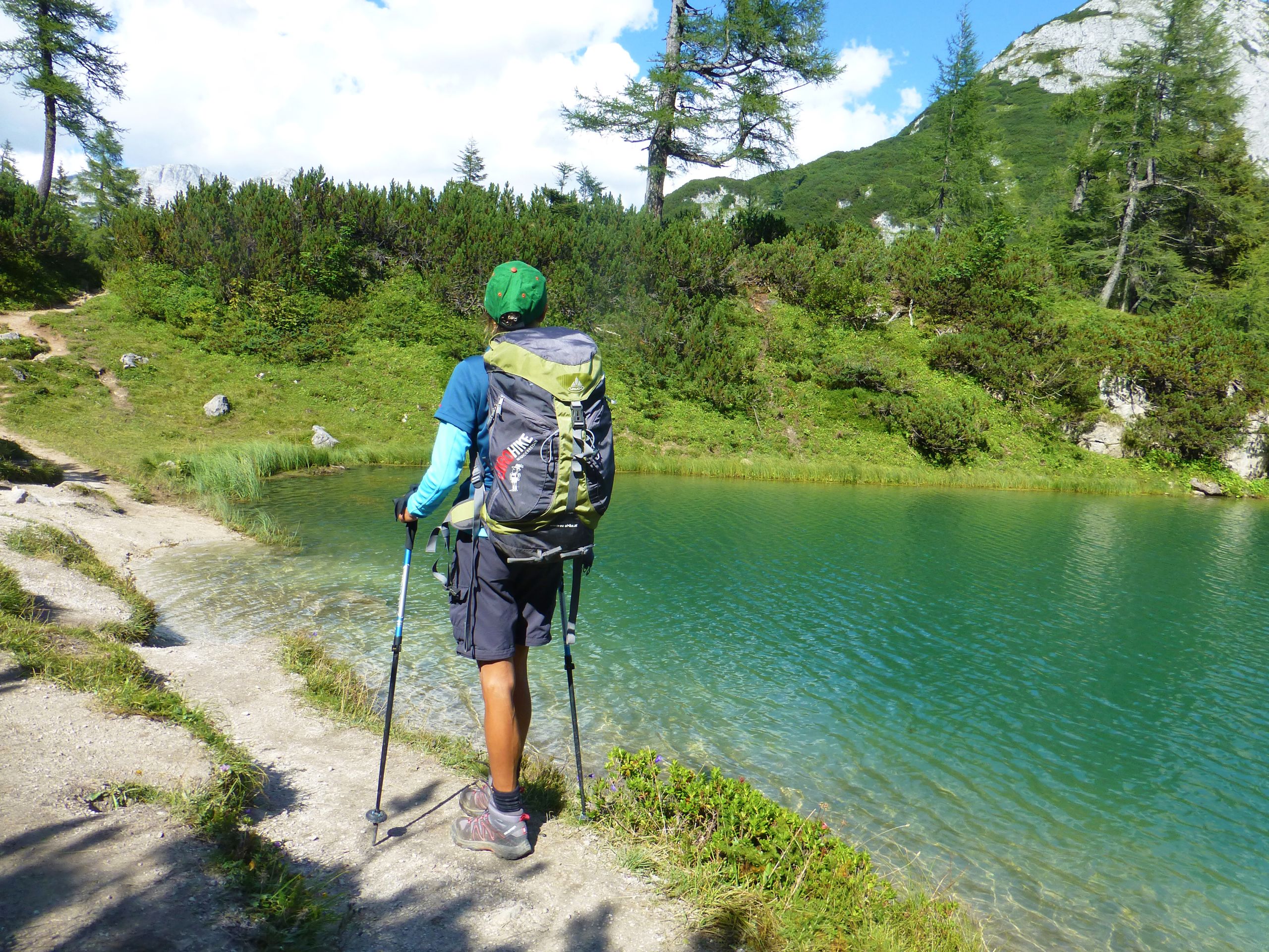 Escursionista che cammina lungo il sentiero vicino a un lago alpino nel Salzkammergut, Austria.