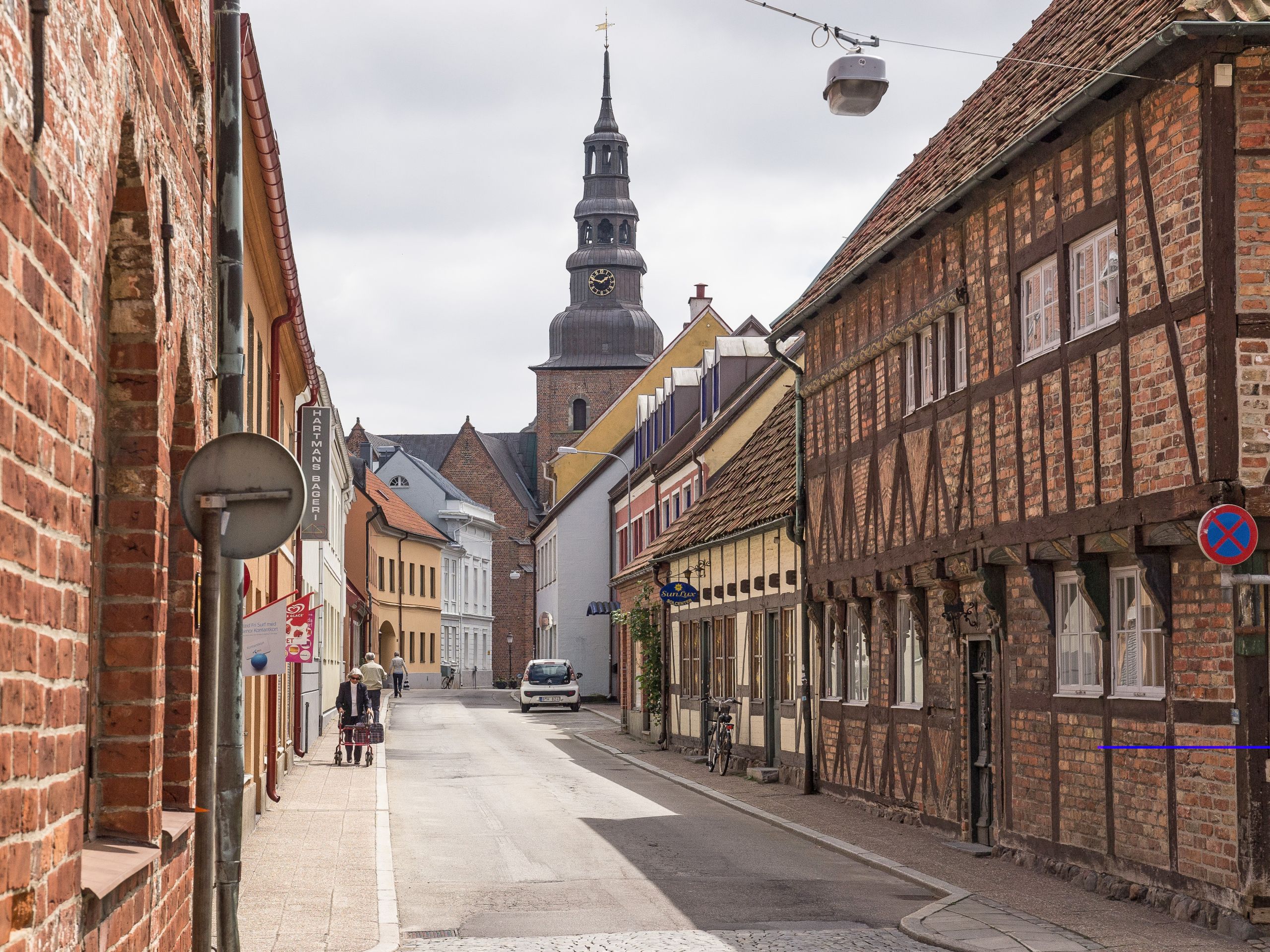Strada acciottolata nel centro storico di Malmö, Svezia, con edifici storici e campanile.