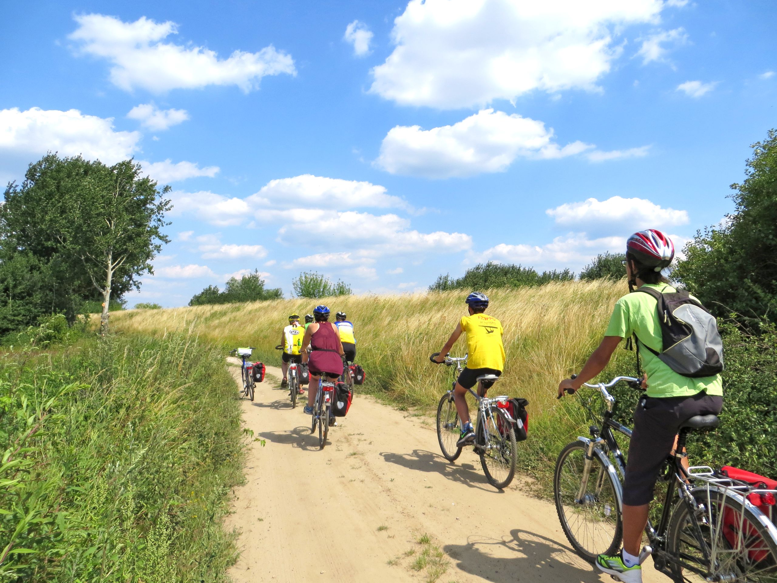 Gruppo in bicicletta in viaggio con Girolibero lungo un sentiero sterrato tra i paesaggi rurali della Polonia.
