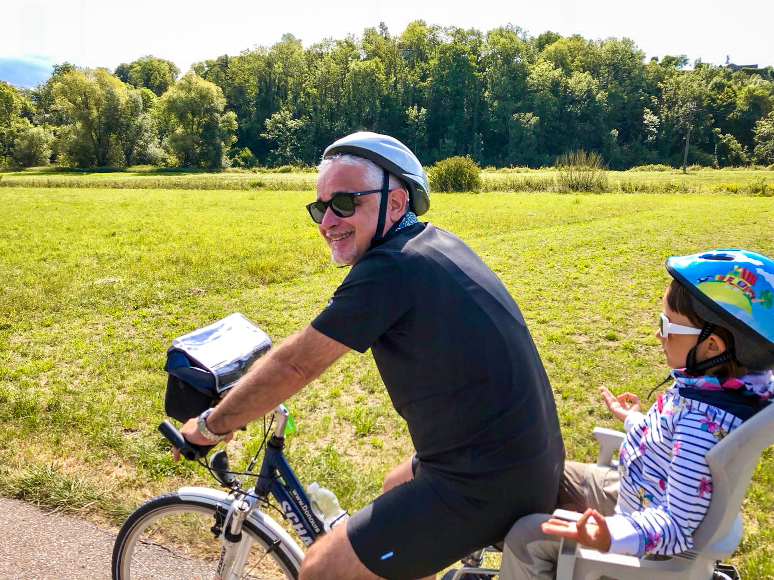 Papà in bicicletta con figlia nel seggiolino lungo la ciclabile in Germania.