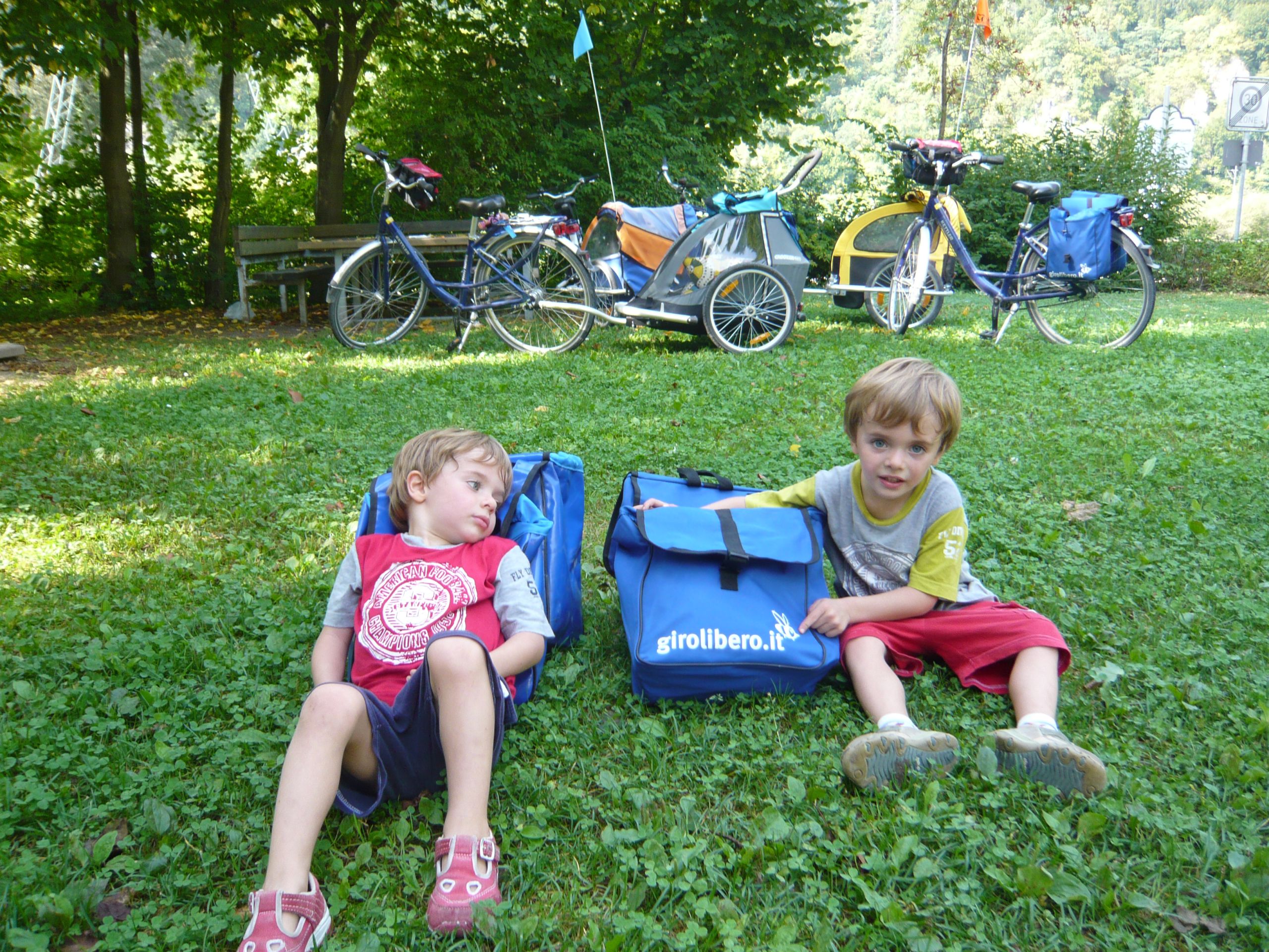 Due bambini seduti sull’erba vicino alle bici durante una pausa in un parco della Germania.