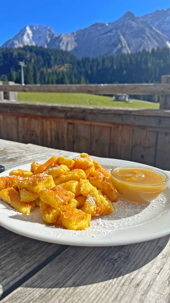 Piatto di spätzle con salsa, piatto tipico bavarese, servito all’aperto con vista sulle montagne.