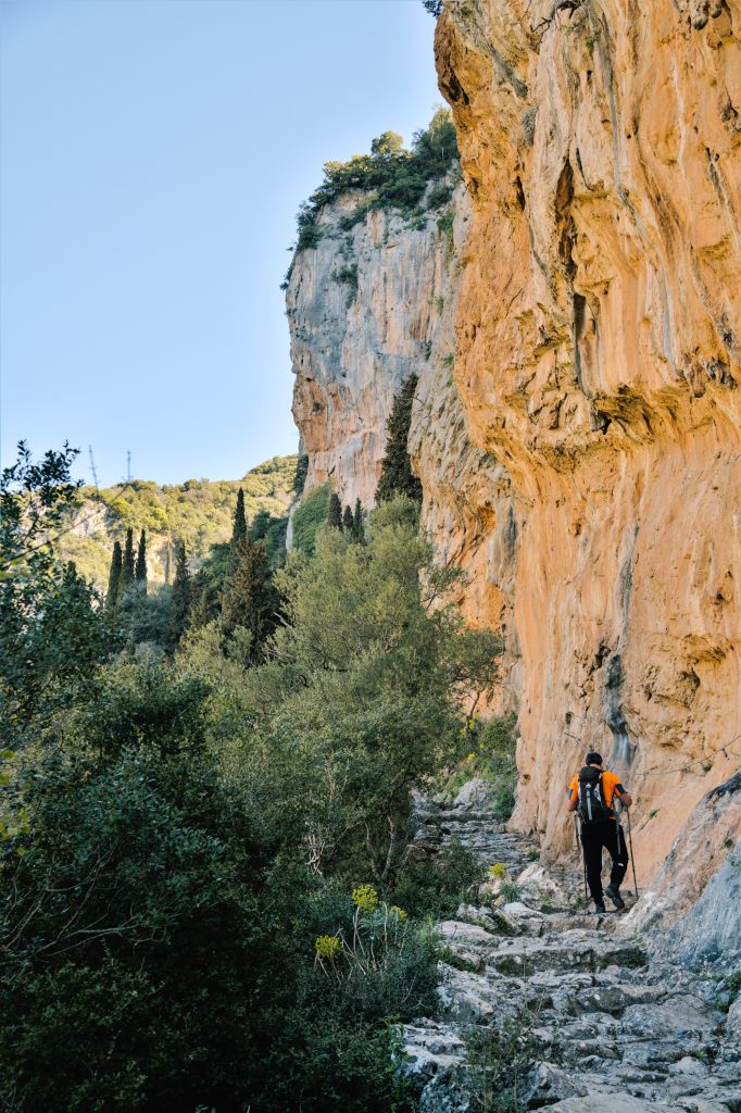 Escursionista su un sentiero roccioso vicino a una parete di montagna nel Peloponneso