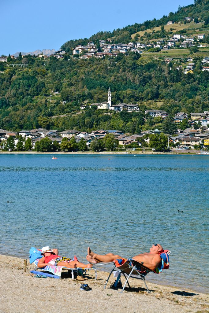 Bagnanti si godono il sole su una spiaggetta del lago di Caldonazzo