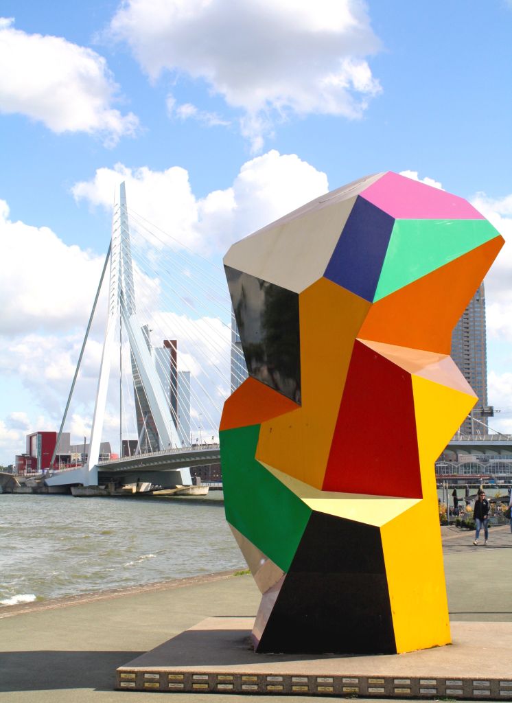 Scultura colorata vicino al Ponte Erasmus a Rotterdam con il cielo parzialmente nuvoloso.