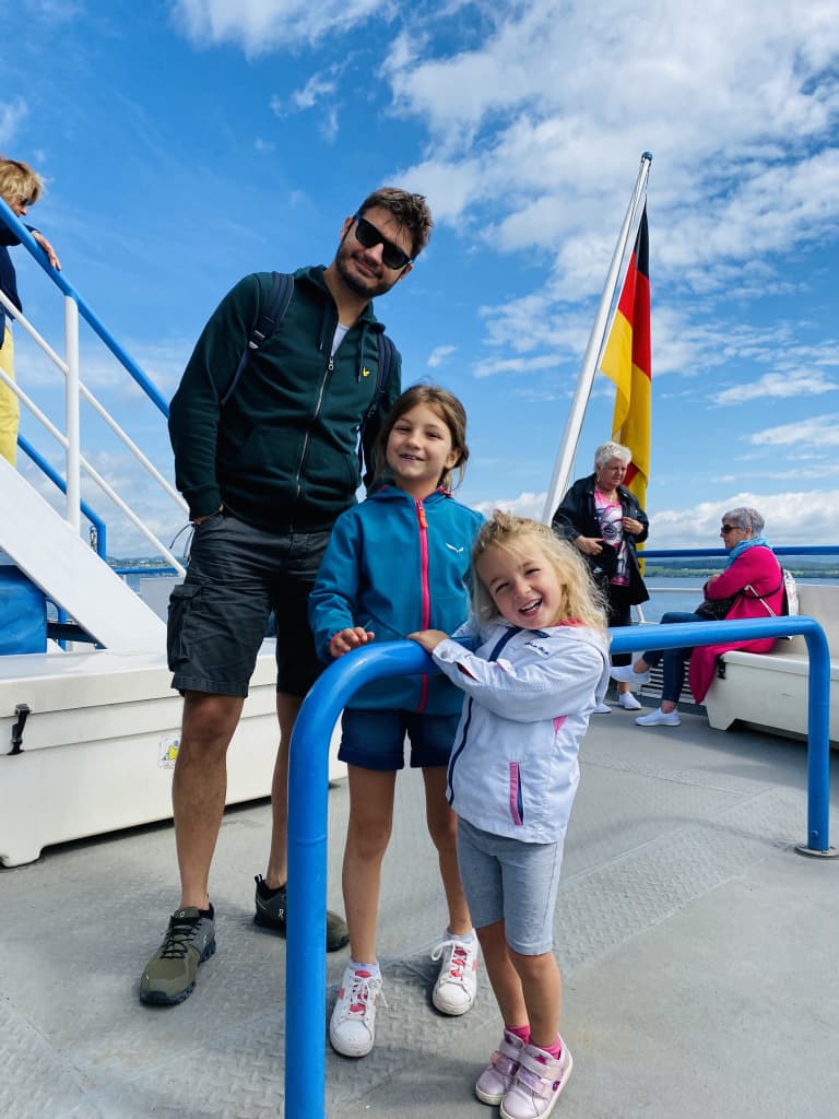 Papà con due bimbe felici durante un giro in barca, vacanze per famiglie in bici e barca