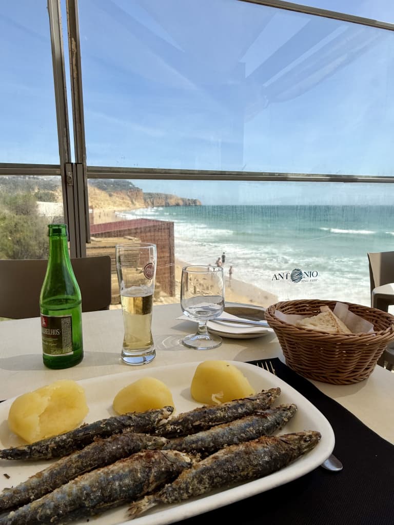 Piatto di sardine alla griglia con patate e vinho verde in un ristorante vista oceano a Sagres, specialità gastronomica dell’Algarve.