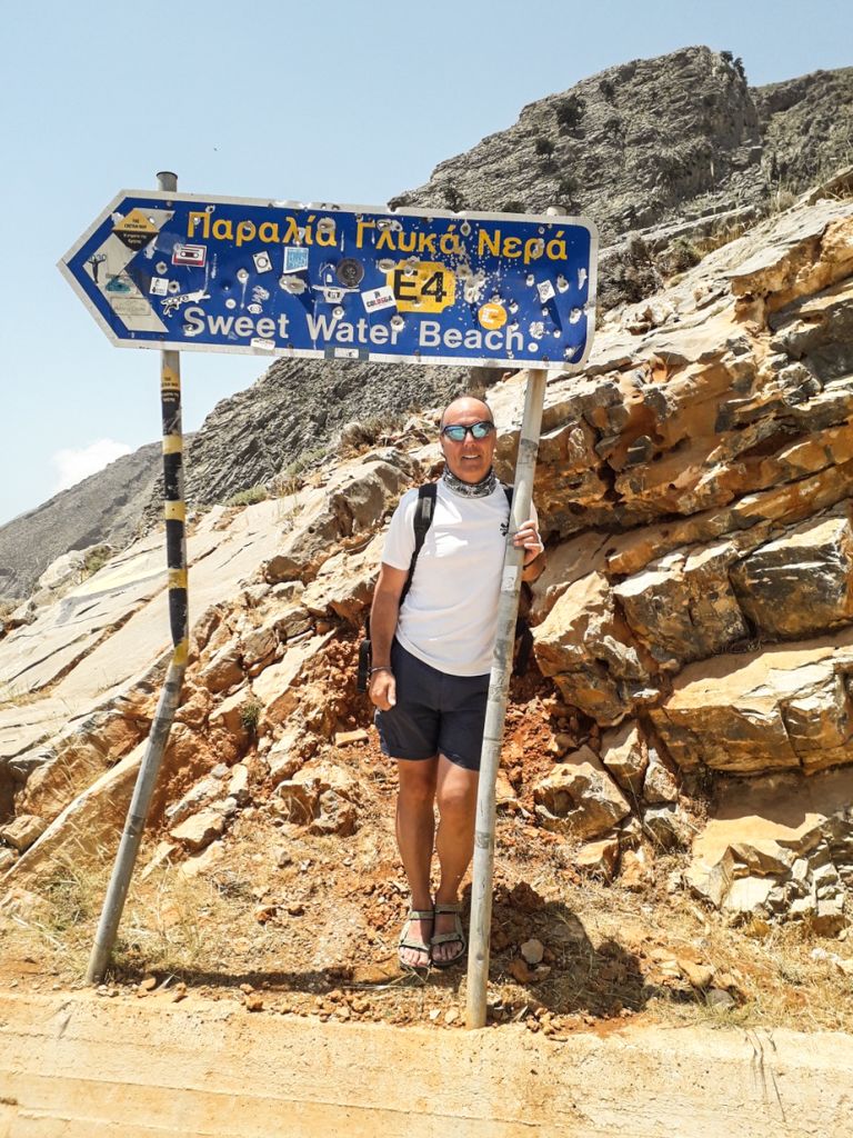 Escursionista accanto a un segnale turistico sull'isola di Creta, trekking in Grecia.