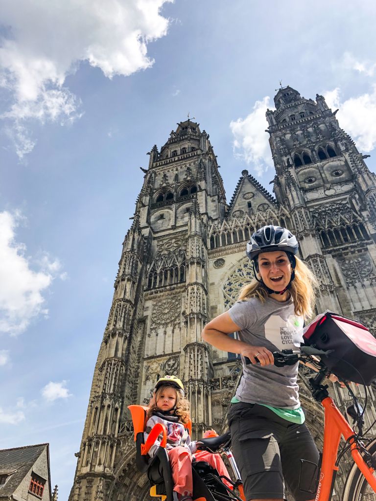 Mother and little daughter on a bike Girolibero take a pic in front of Tours Cathedral, France