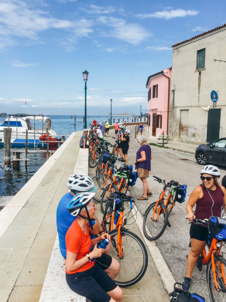 Ciclisti in viaggio con Girolibero che si riposano lungo il canale di Chioggia, Italia.