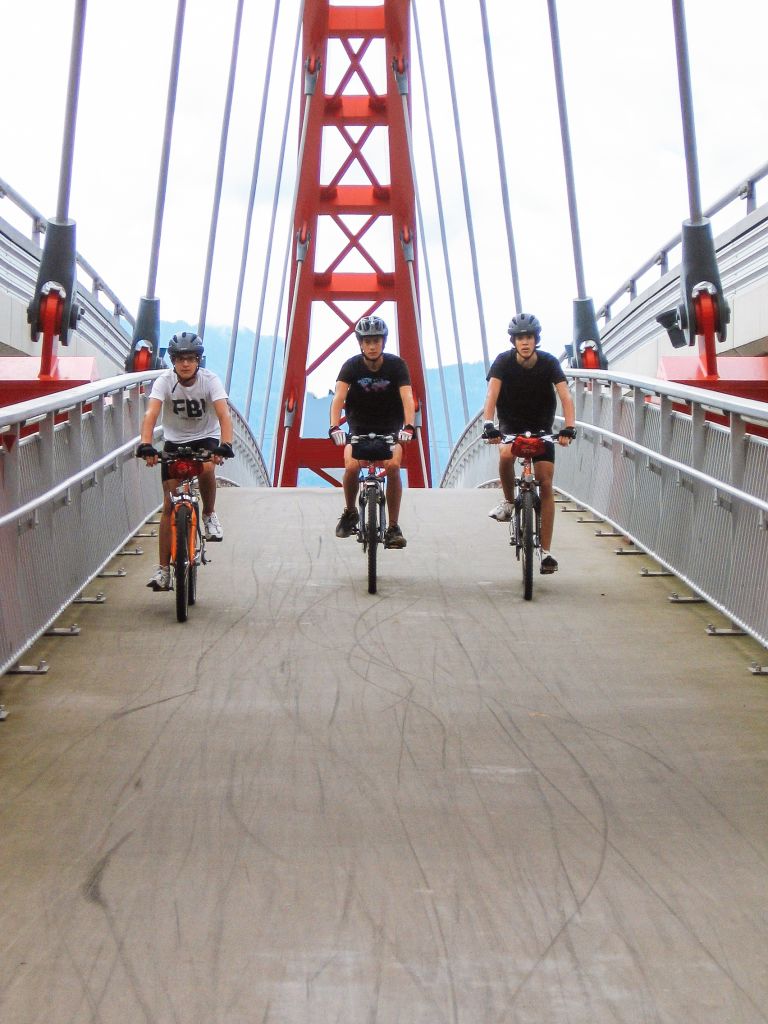 Gruppo di cicloturisti con caschetto, ponte rosso e bianco, vacanza all'aria aperta, Austria