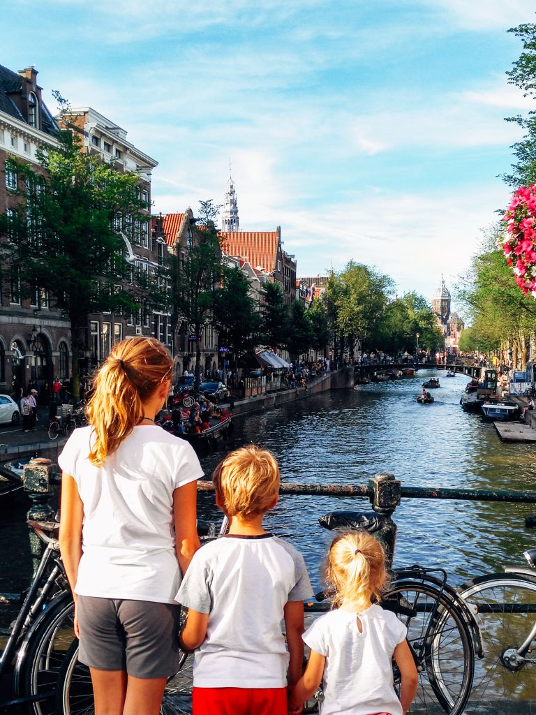 Ragazzi che osservano un canale ad Amsterdam, biciclette e case tradizionali olandesi