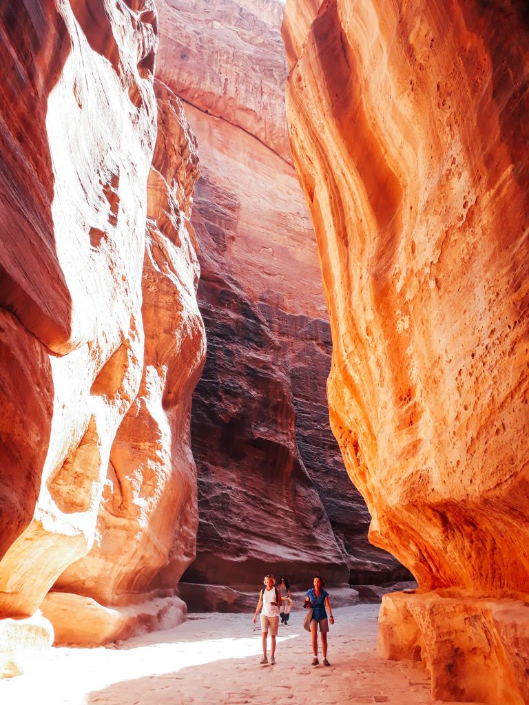Turisti attraversano la gola rocciosa del Siq che conduce a Petra, Giordania.