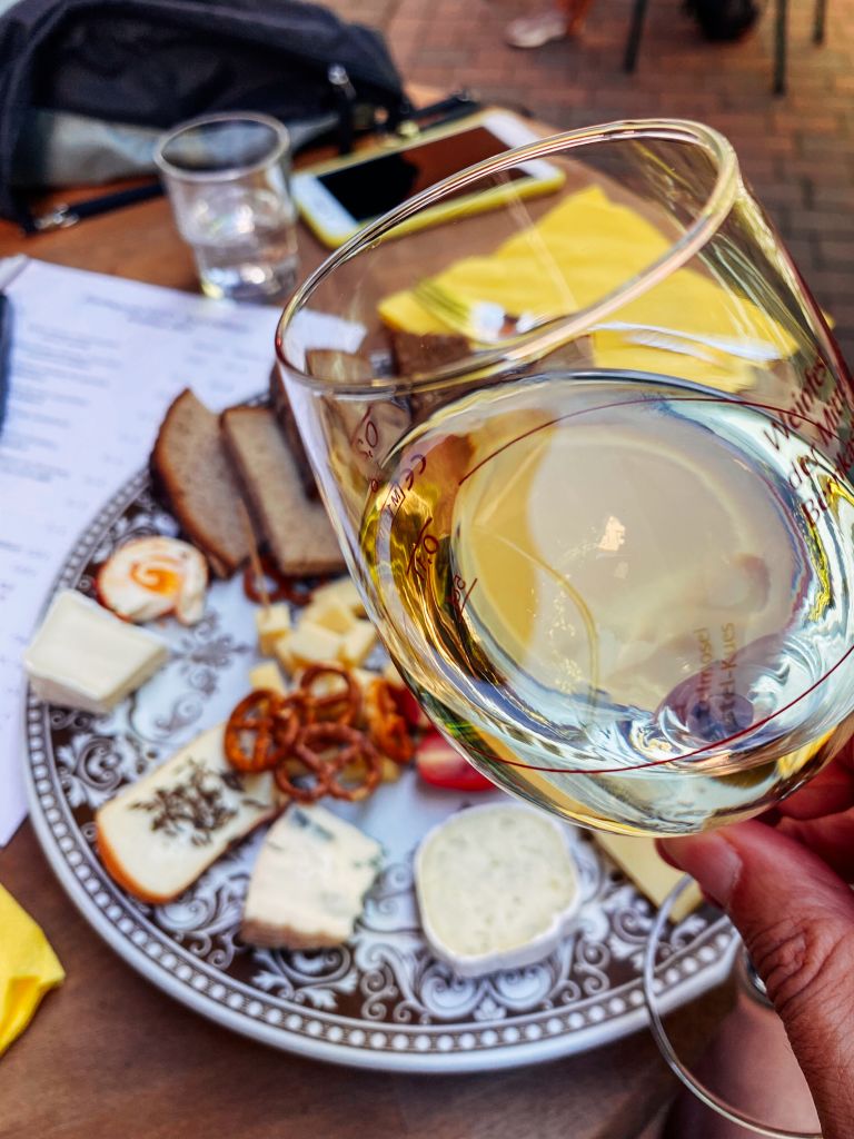 Piatto di specialità tedesche con formaggi, salsicce e bicchiere di vino della Mosella.
