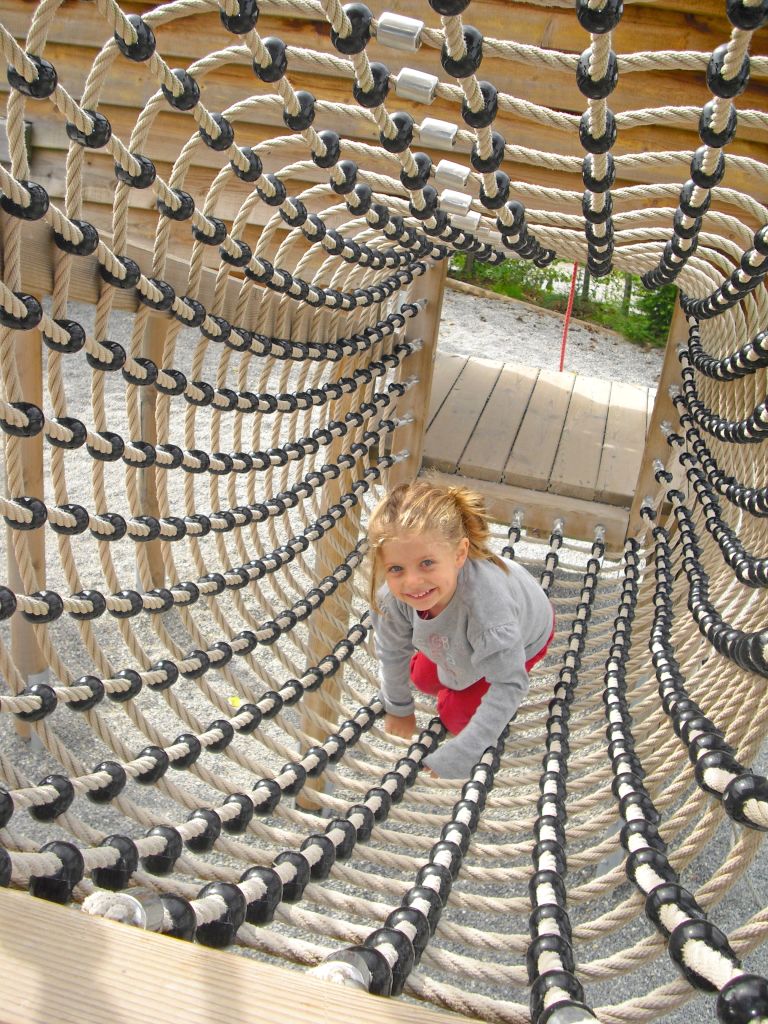 Bambino che gioca in struttura di legno e corde, attività per famiglie sul Lago di Costanza.