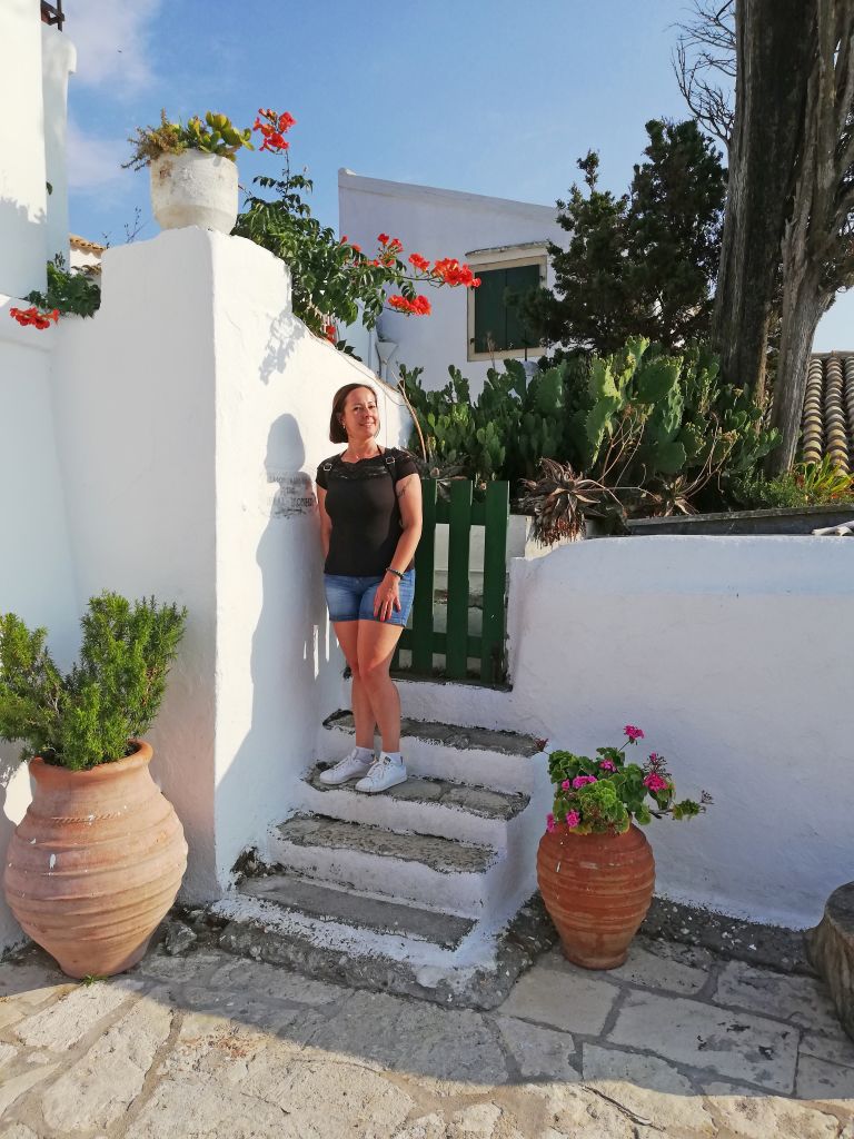 Turista in posa sulle scale di una casa bianca a Corfù, Grecia