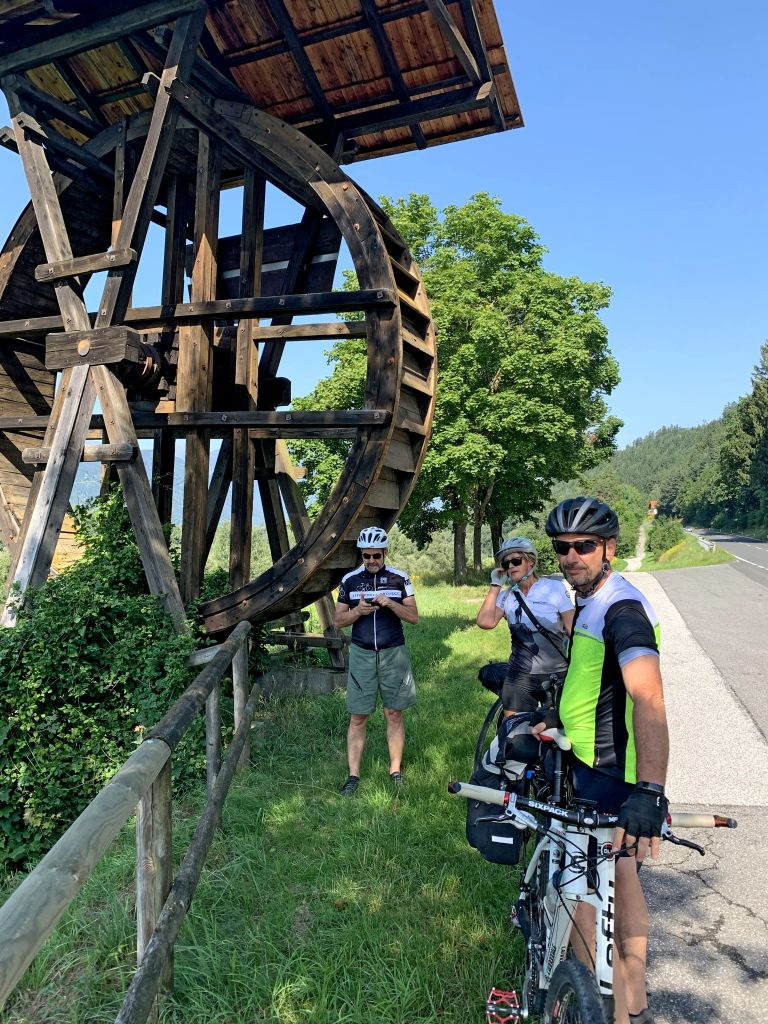 Ciclisti accanto a una vecchia ruota di mulino in Tirolo, Austria.