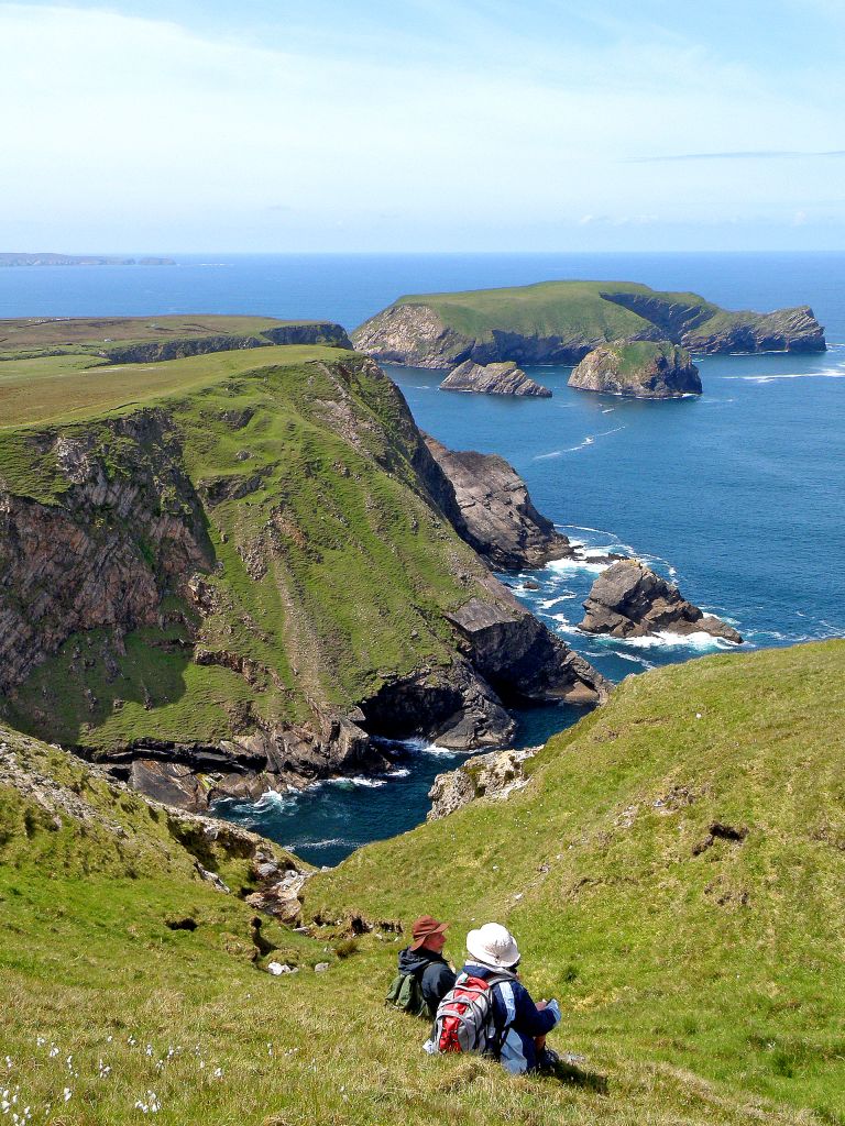 Escursionisti lungo le scogliere costiere, con vista su formazioni rocciose e oceano, vacanze a piedi "Girolibero" in Irlanda del Nord
