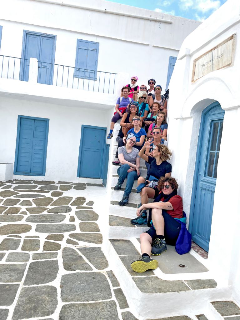 Gruppo di viaggiatori Girolibero seduto sul gradino di un vicolo nell'isola di Sifnos.