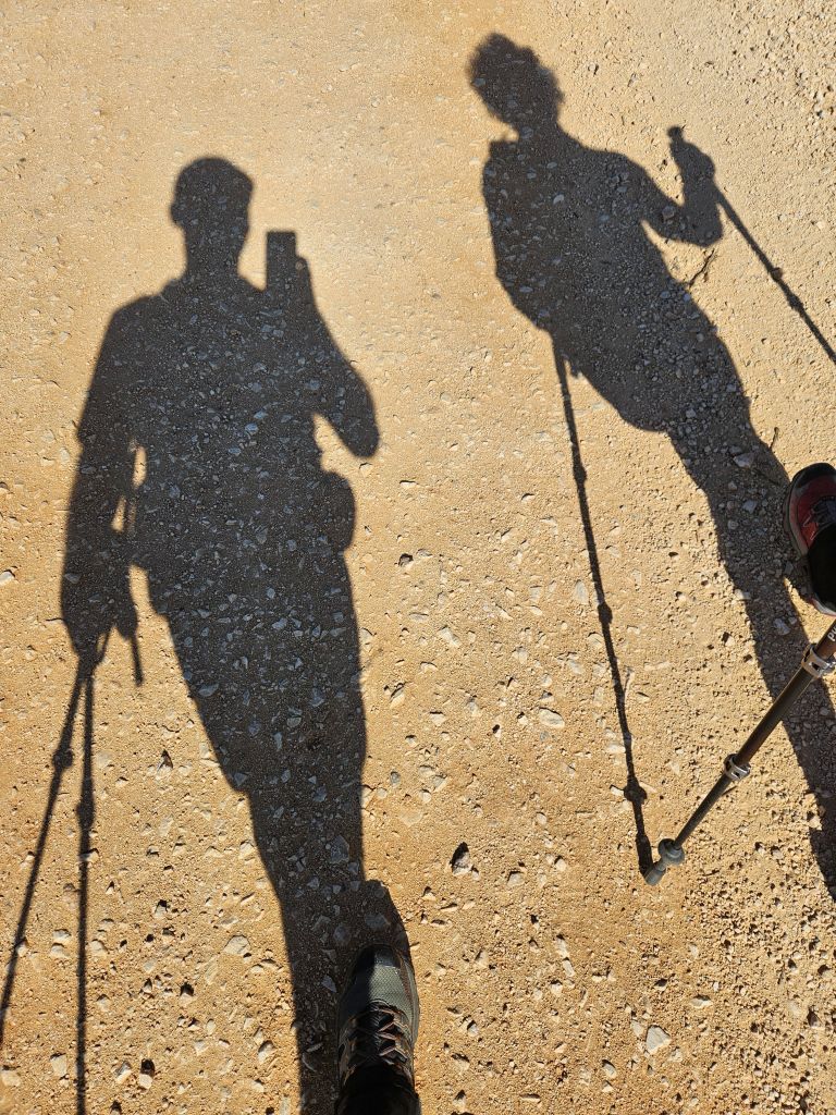 Ombre di camminatori con bastoncini nordic walking su sentiero sterrato in Algarve, Portogallo.