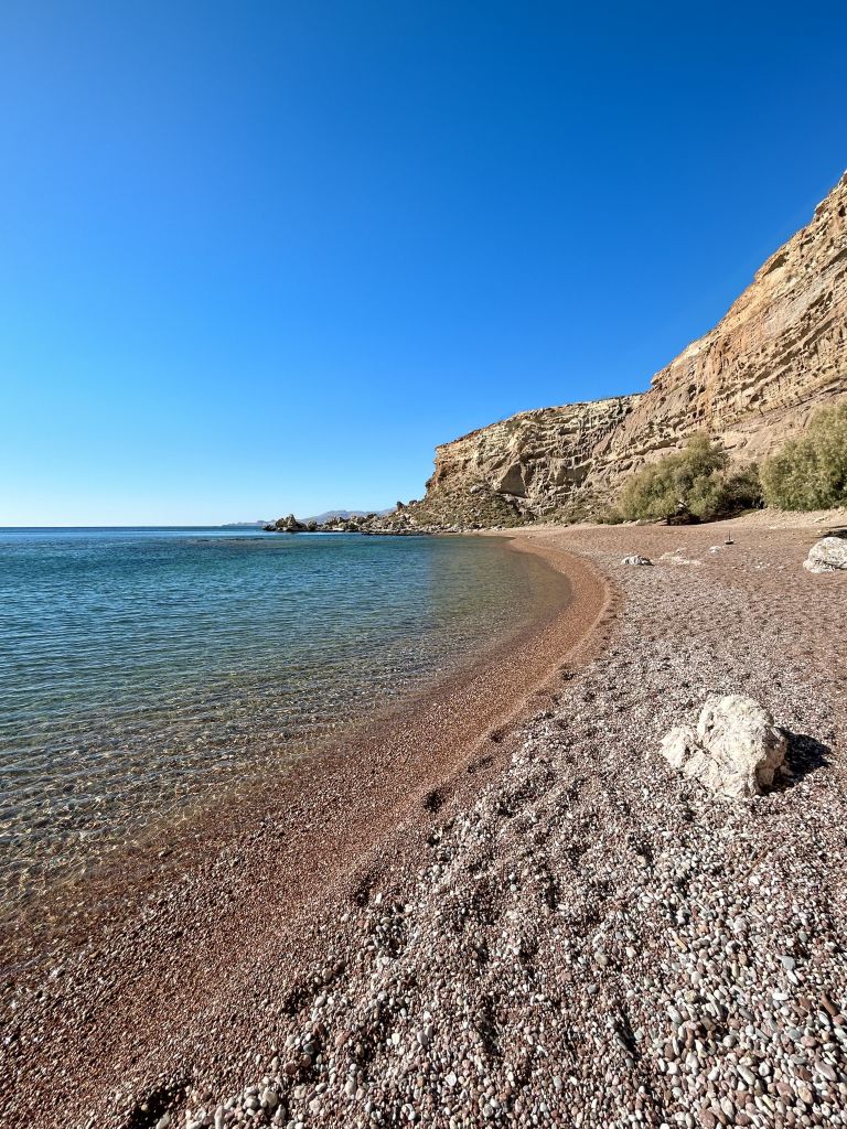 Spiaggia di ciottoli a Capo Prasonisi con mare cristallino e costa rocciosa, Rodi, Grecia.