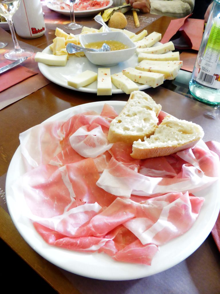 Tagliere di prosciutto crudo, formaggi e pane tipico, specialità italiane.